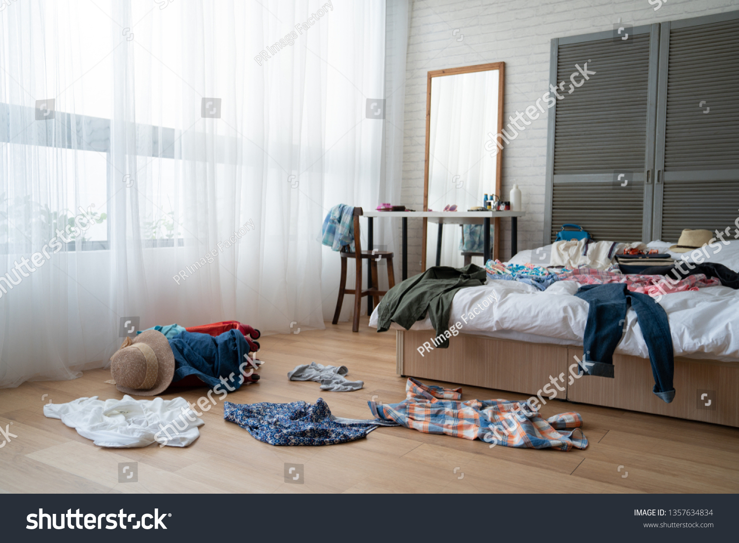 straw hat and colorful clothes in luggage on wooden floor. empty nobody in messy white bed in bedroom packing suitcase for travel abroad summer vacation holidays. mirror by window at dressing table. #1357634834