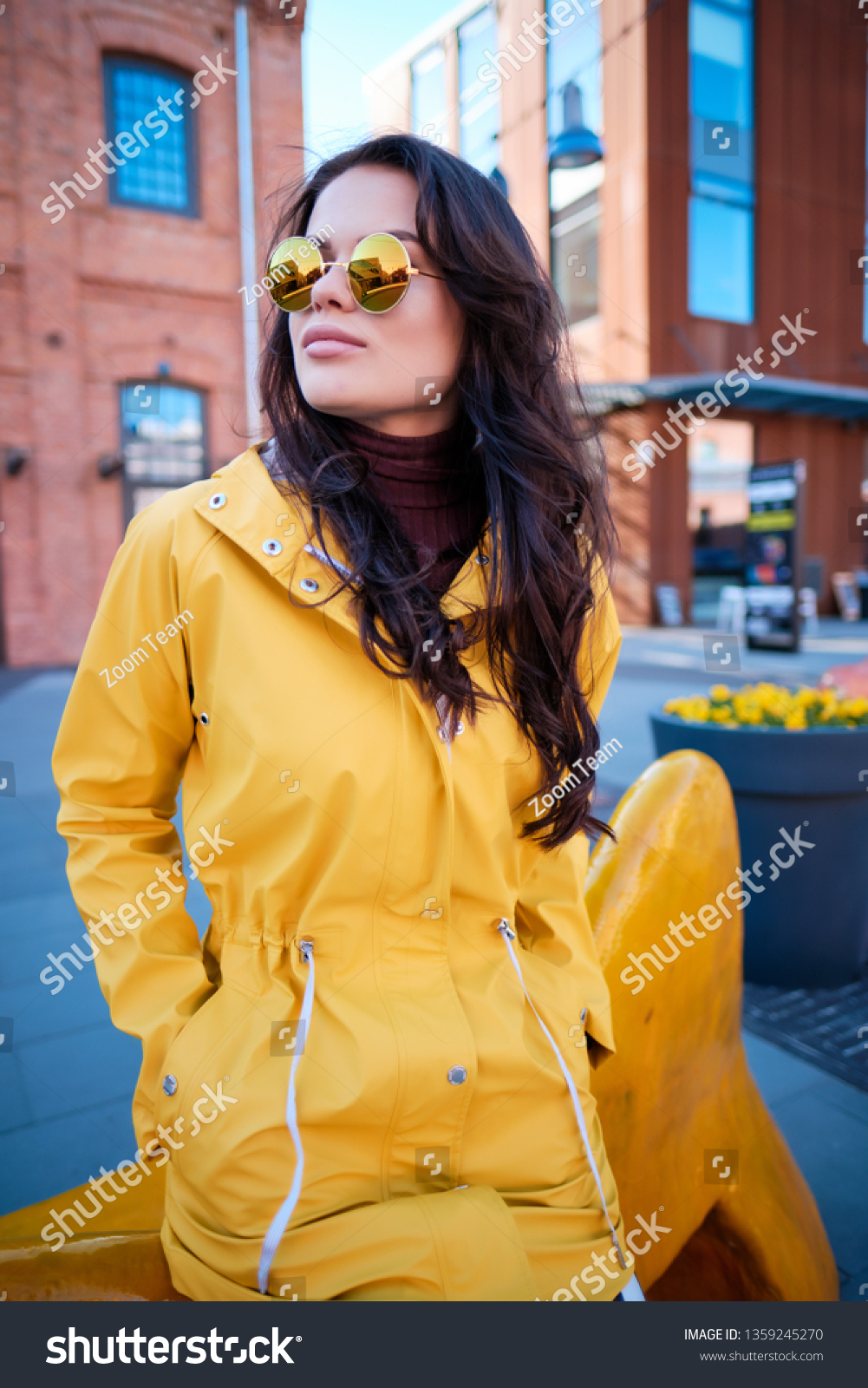 Attractive hipster young woman in stylish sunglasses in a stylish yellow coat #1359245270