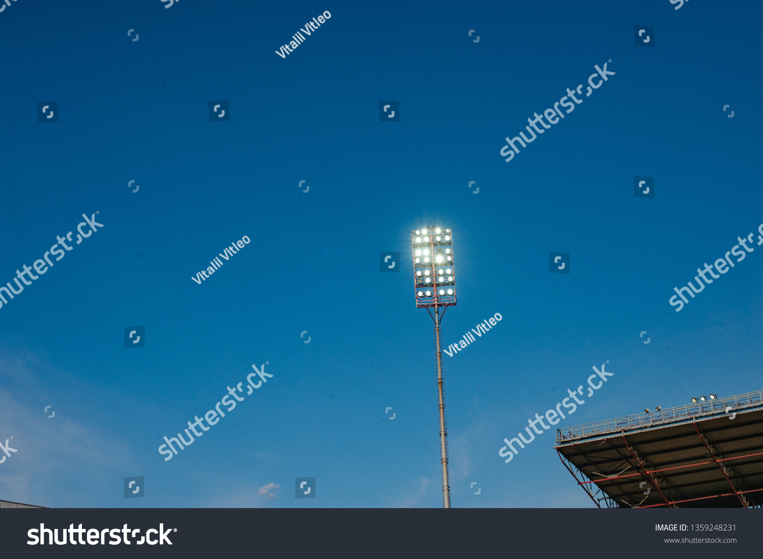 Floodlights with a metal pole for the sports arena. Tall high outdoor stadium spotlights on rigid frame construction with blue sky background #1359248231