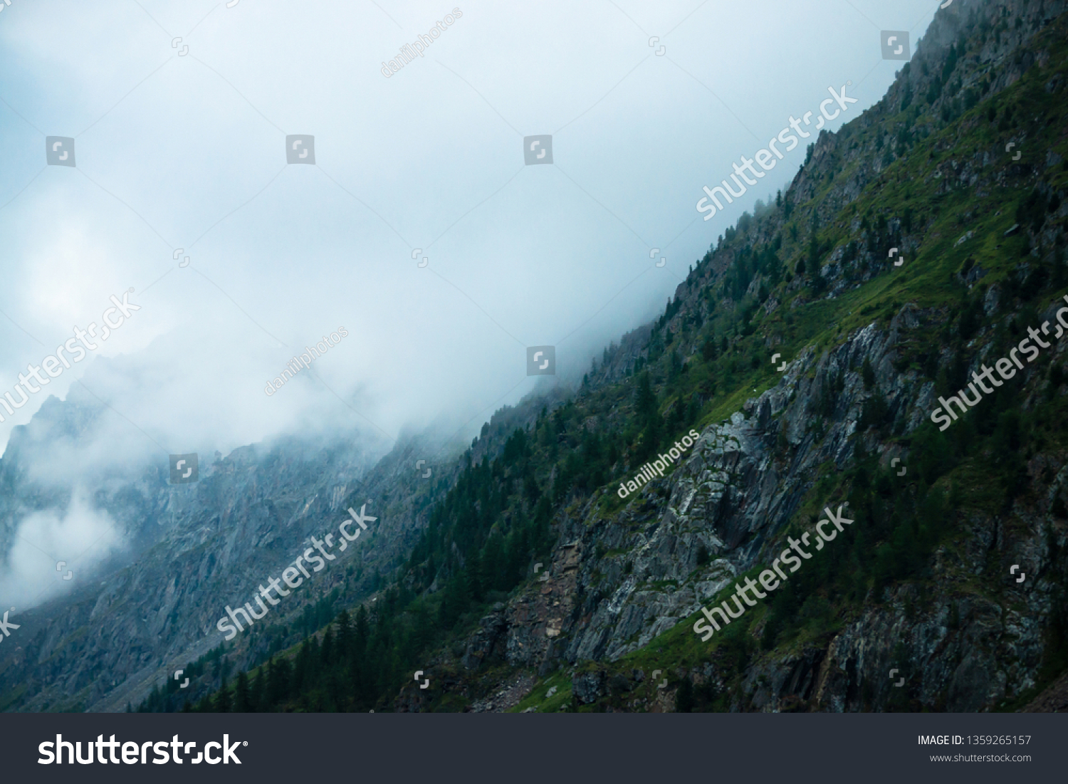 Ghostly giant rocks with trees in thick fog. Mysterious huge mountain in mist. Early morning in mountains. Impenetrable fog. Dark atmospheric eerie landscape. Tranquil mystic atmosphere of wilderness. #1359265157