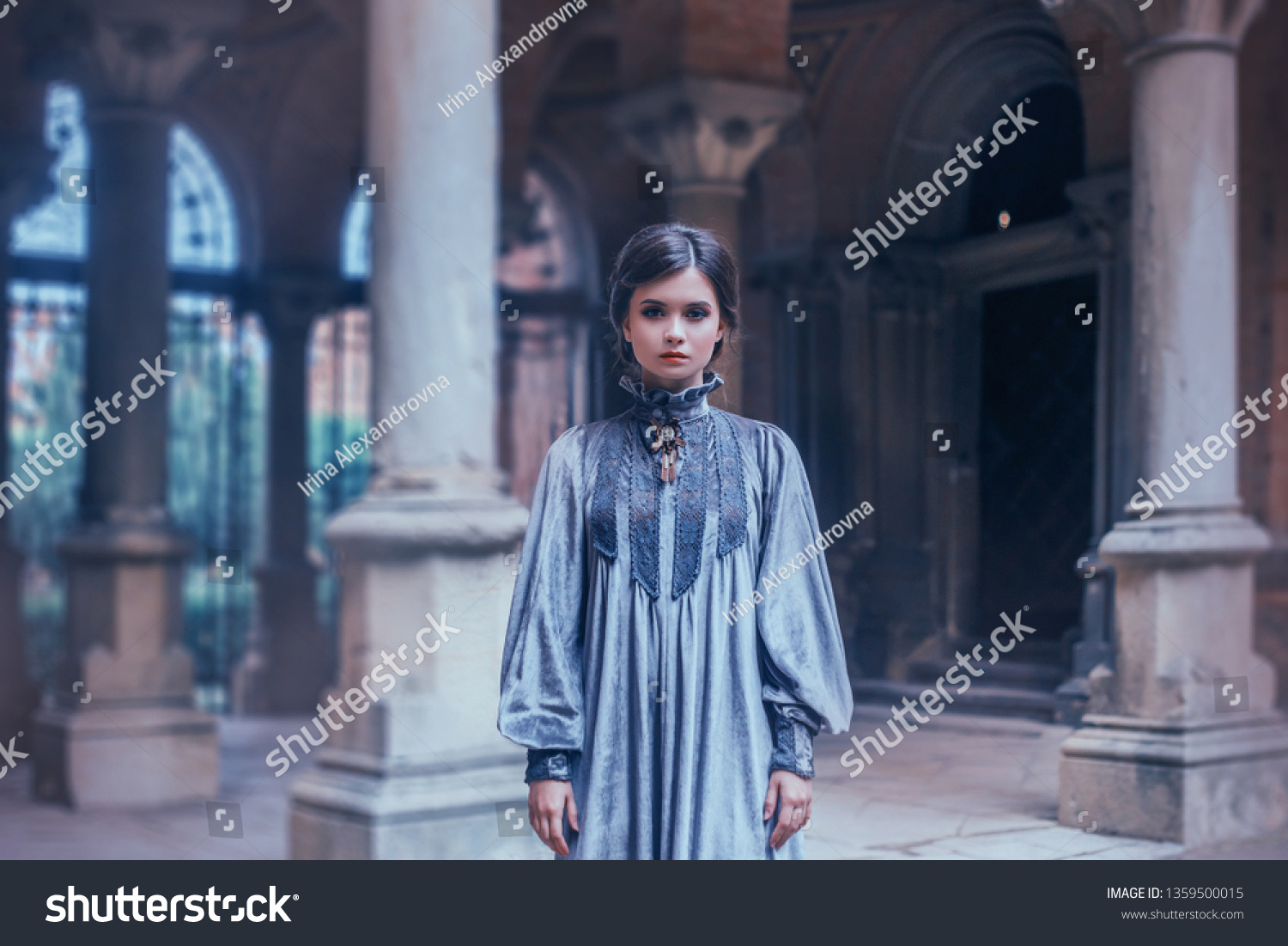 Strict teacher in a gray velvet vintage dress looking into the camera. Overseer psychological wedge strictly mode. Art photography, depressed mood. Background gothic architecture with columns #1359500015