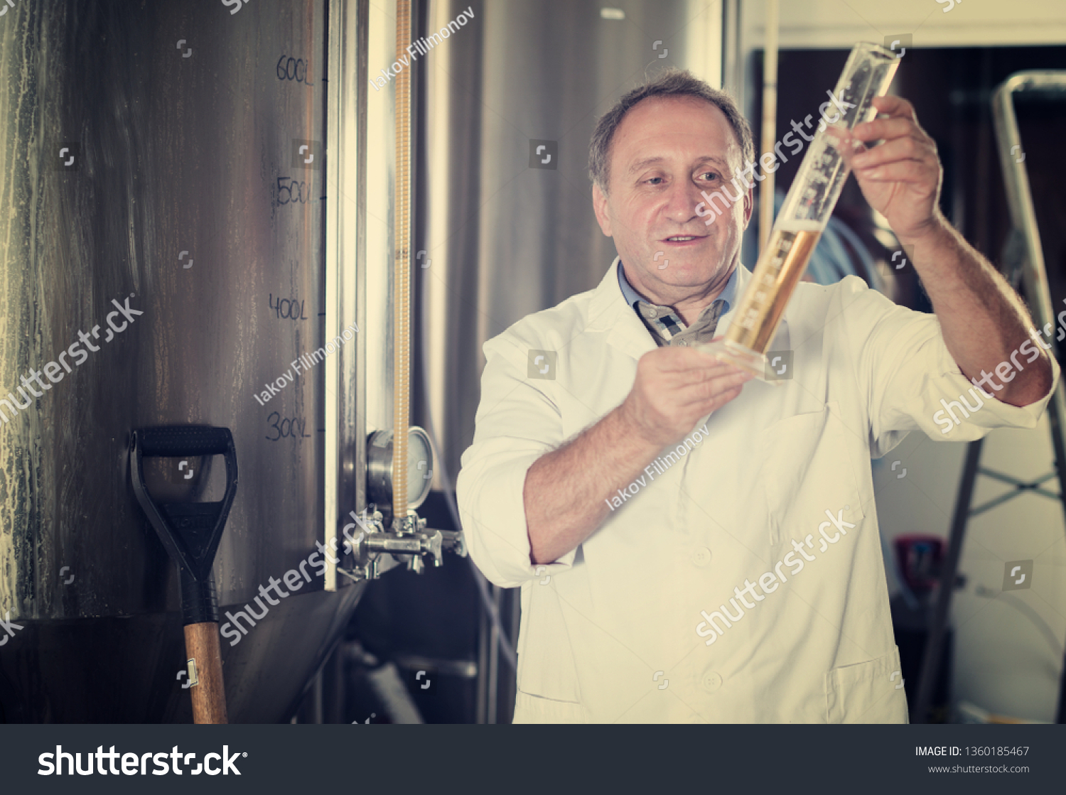 Man expert is analizying the quality of beer in flask in laboratory. #1360185467
