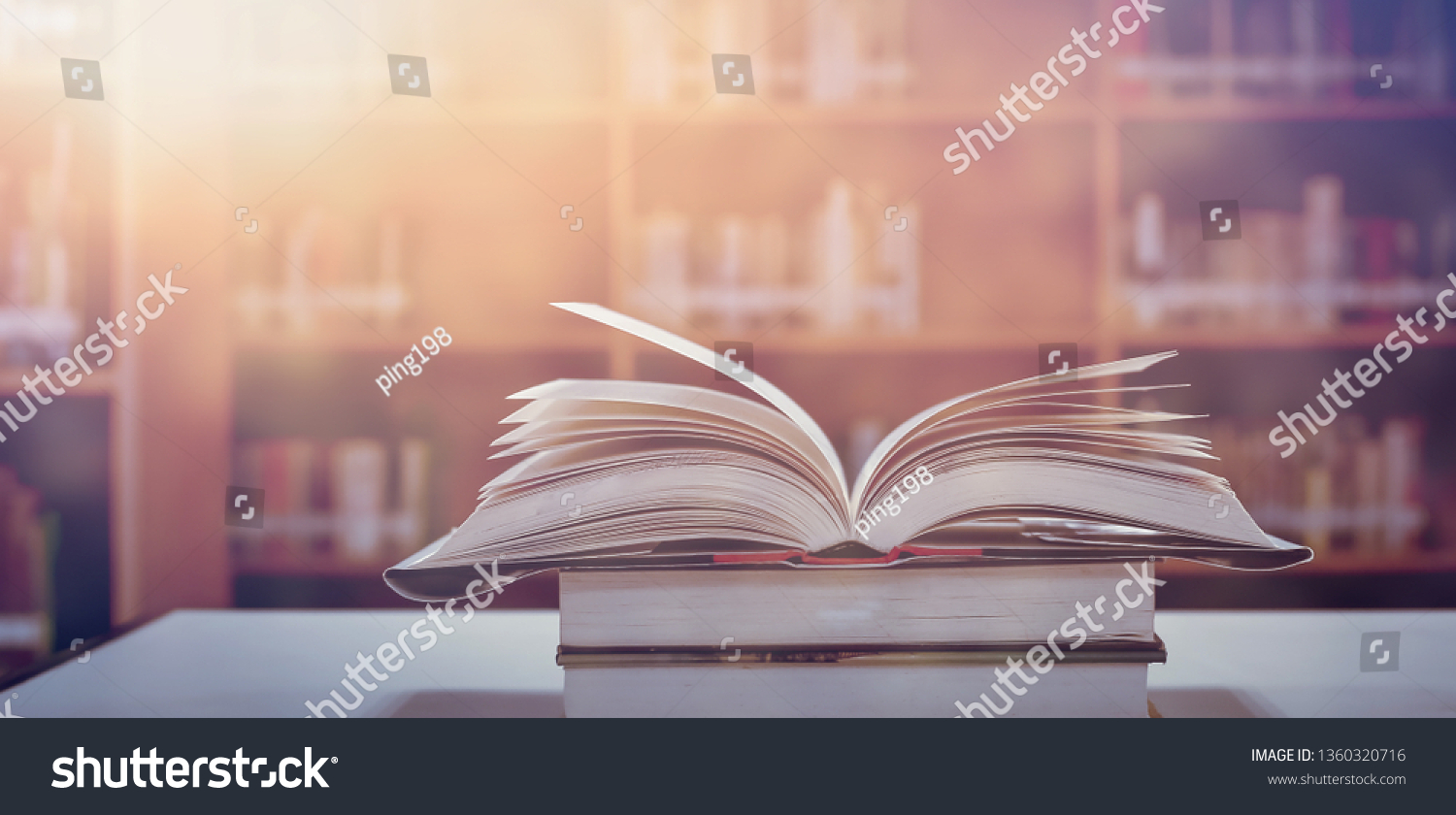 Book in library with old open textbook, stack piles of literature text archive on reading desk, and aisle of bookshelves in school study class room background for academic education learning concept #1360320716