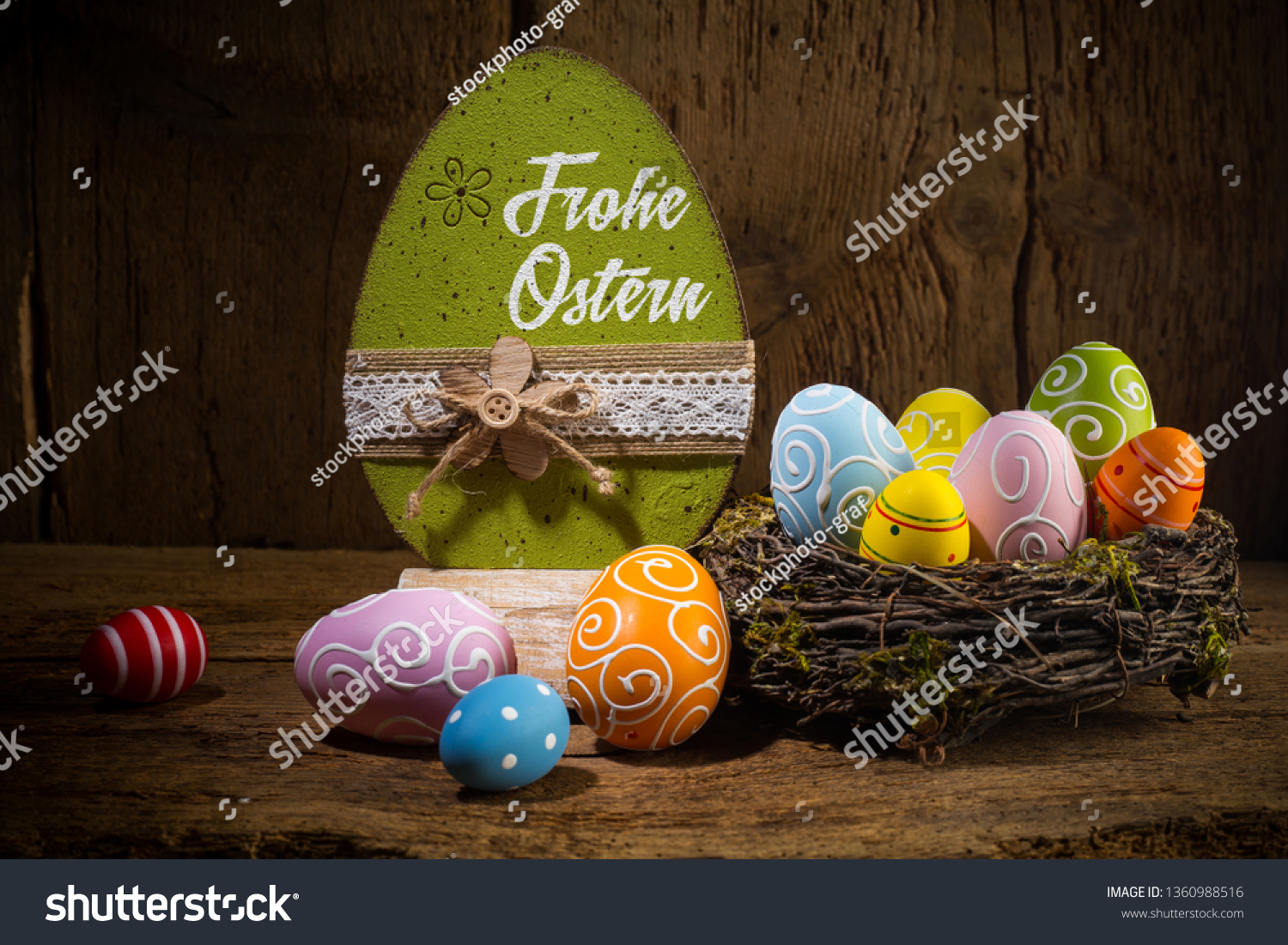 German greetings Frohe Ostern ( english translation happy easter ) Colorful painted eggs in birds nest basket on rustic wooden old  greeting card background #1360988516