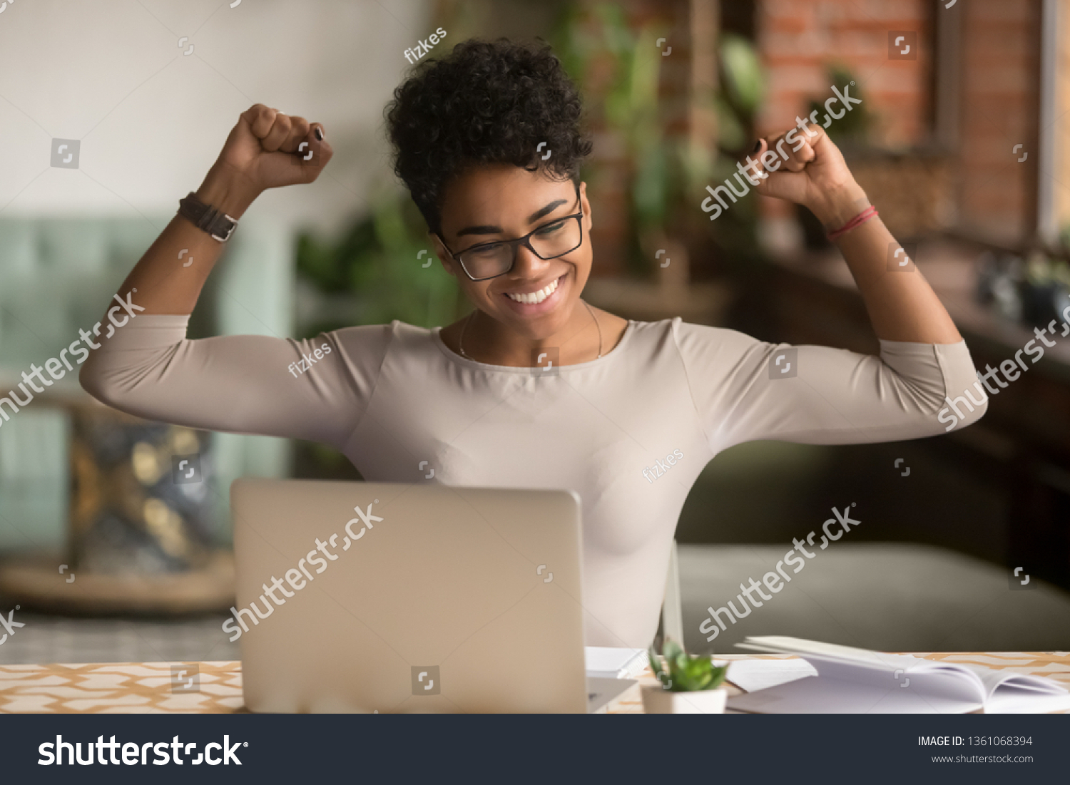 Excited happy african american woman feeling winner rejoicing online win got new job opportunity, overjoyed motivated mixed race girl student receive good test results on laptop celebrating admission #1361068394