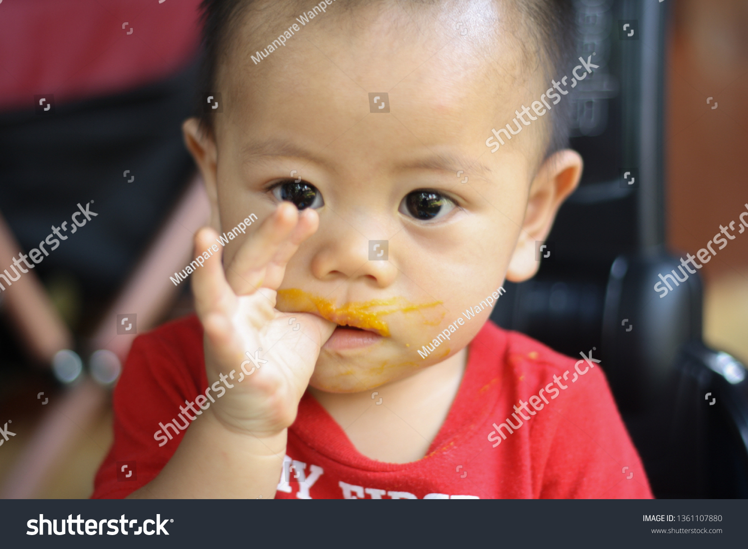 portrait of a little Asian boy eating a baby with a hand and a grimy face #1361107880
