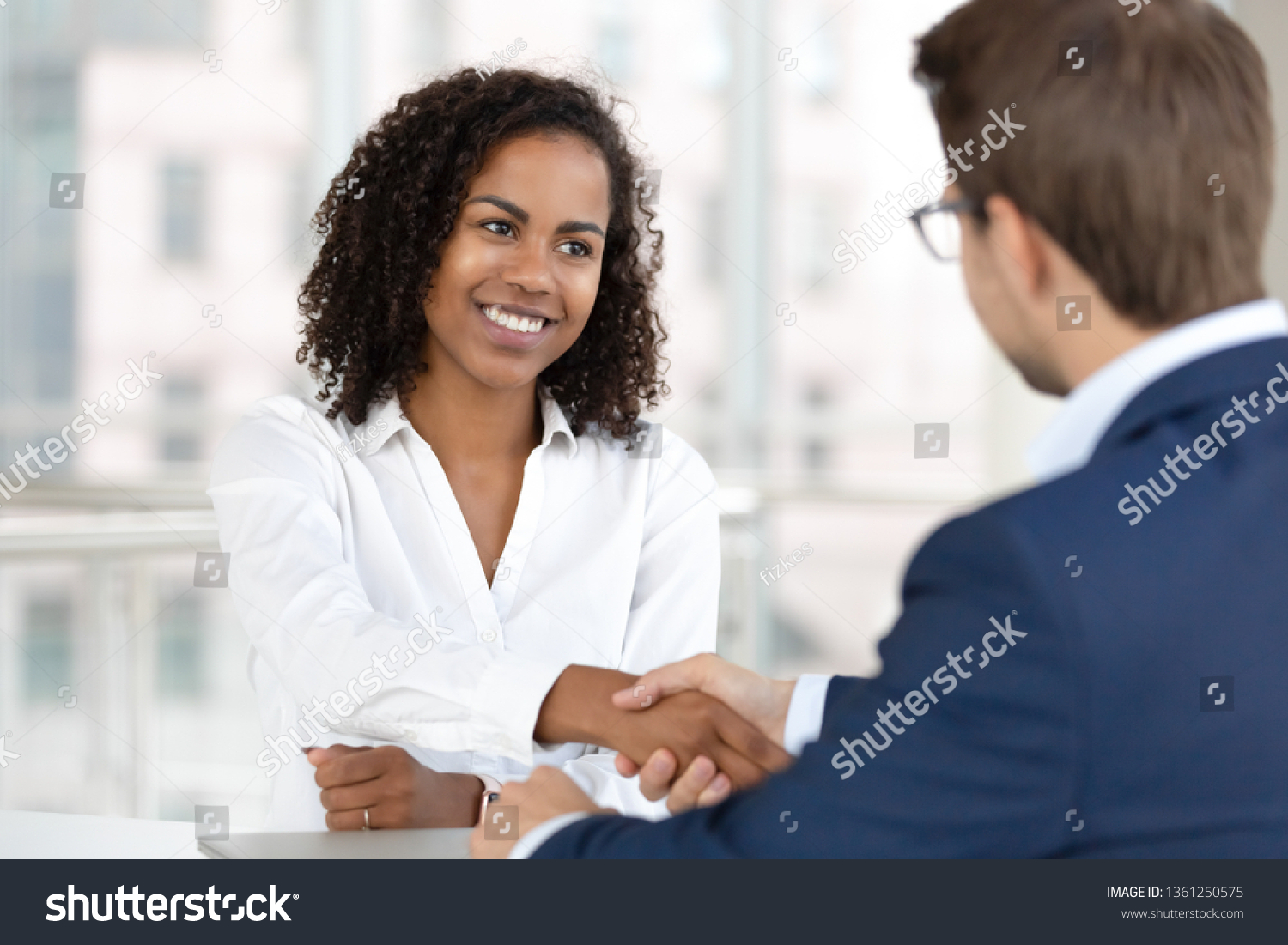 Smiling african female hr manager handshake hire male candidate at job interview make good first impression, happy mixed race client shake hand of bank broker, respect, business agreement concept #1361250575