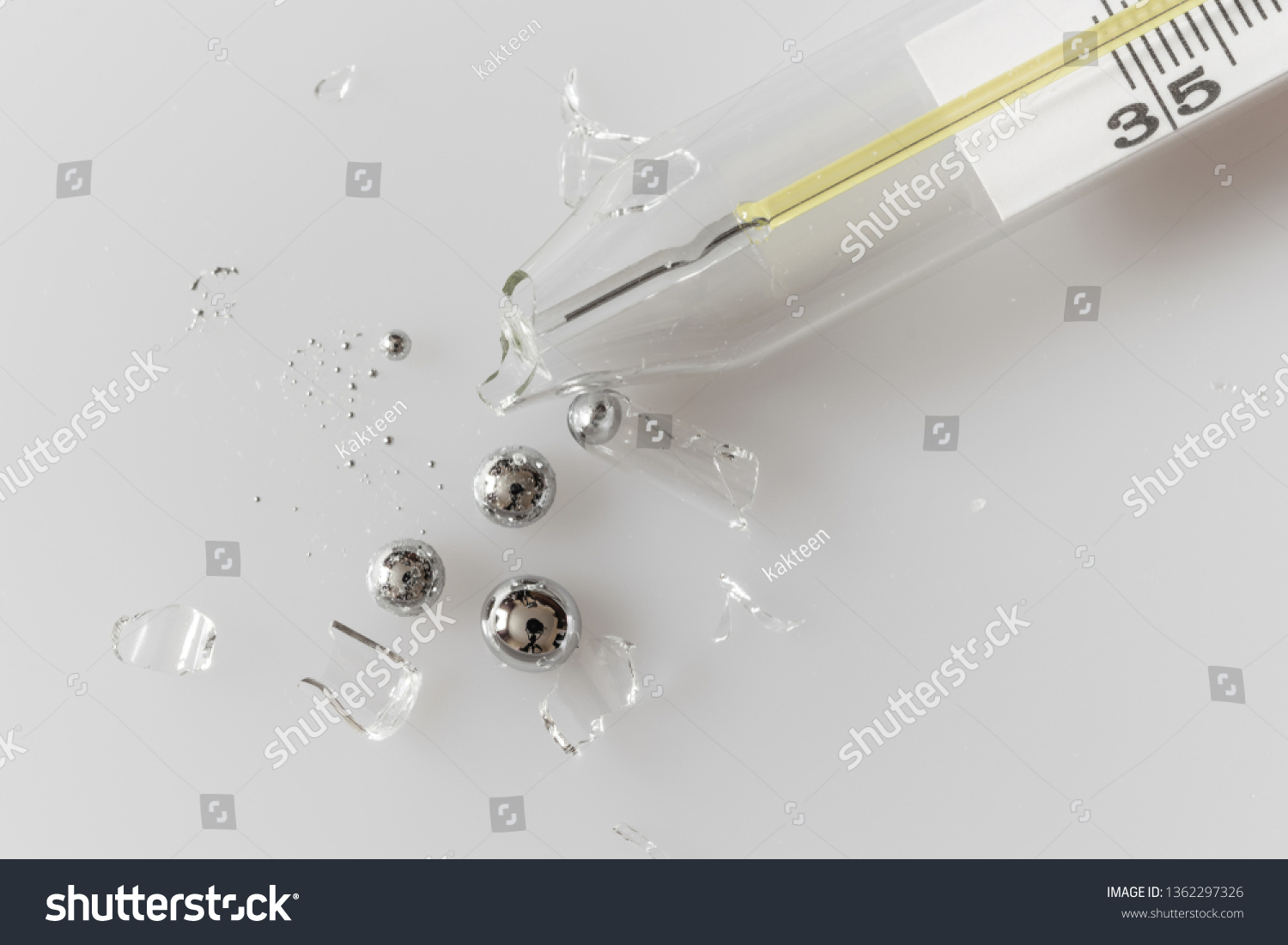 Broken glass mercury thermometer on light grey surface. Mercury drops with glass fragments. Mercury vapor poisoning. #1362297326