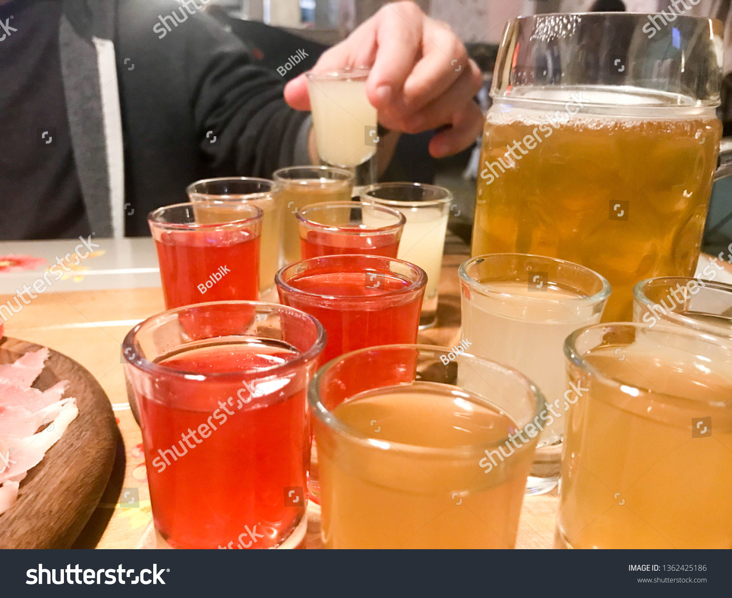 A set of lots of delicious yellow orange red glasses, shots with strong alcohol, vodka, brandy, brandy, beer on wooden stands on a table in a cafe, bar, restaurant. #1362425186