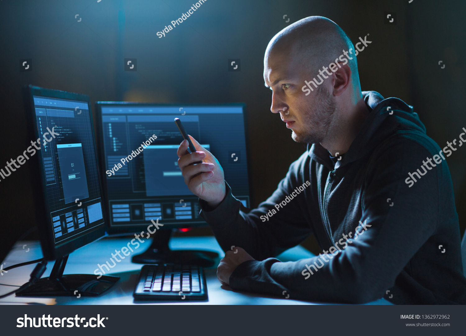 cybercrime, hacking and technology concept - male hacker with smartphone and progress loading bar on computer's screens in dark room #1362972962