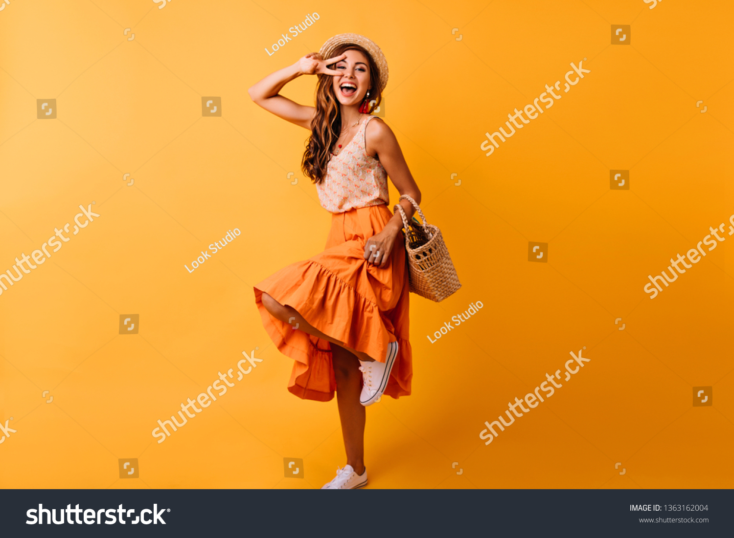 Gorgeous red-haired white woman dancing in studio. Dreamy girl in long skirt having fun on orange background. #1363162004