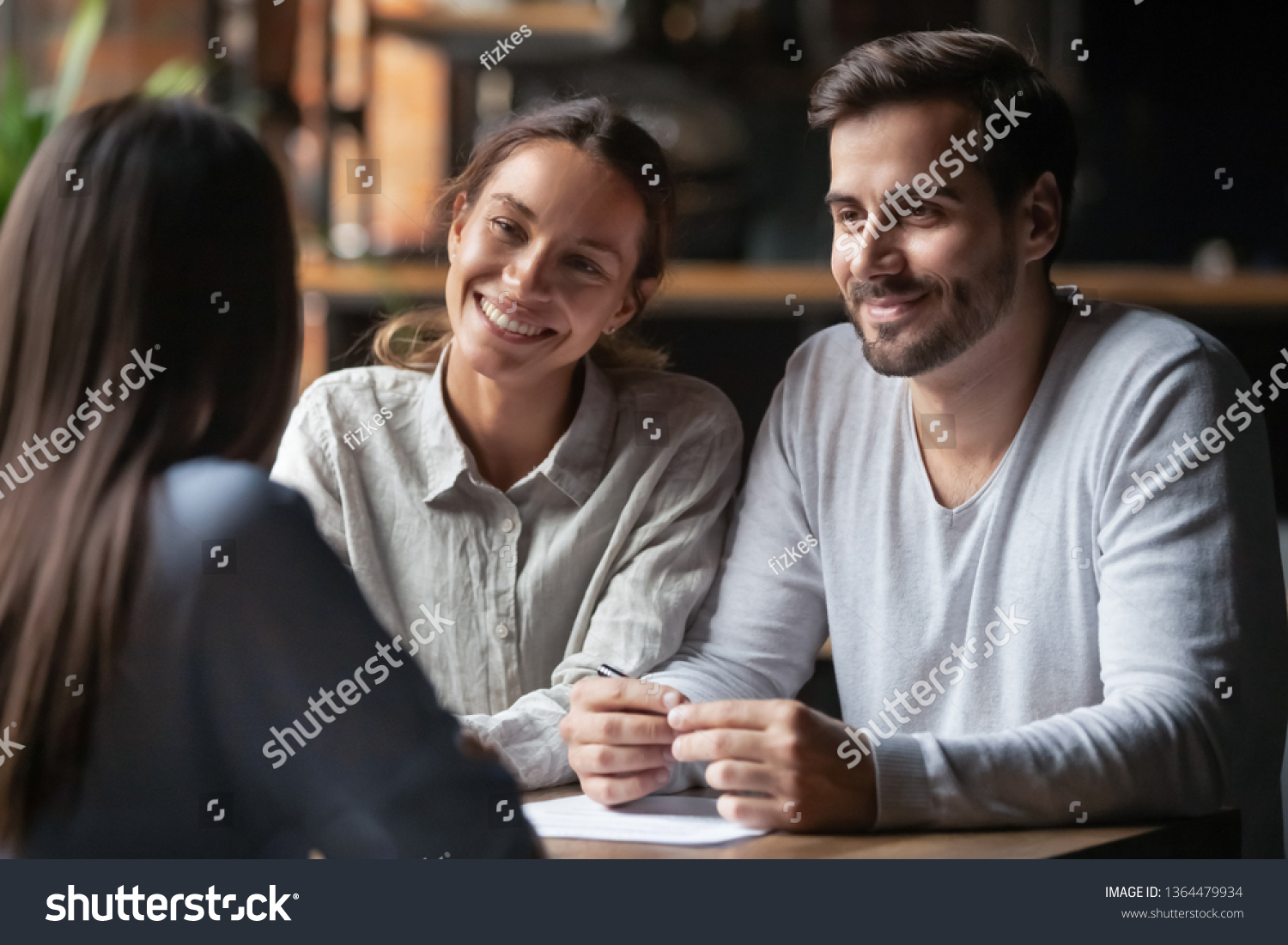 Biracial woman caucasian man listen vacancy candidate sitting together at table at job interview. Diverse couple communicating with real estate agent, successful meeting ready to sign contract concept #1364479934