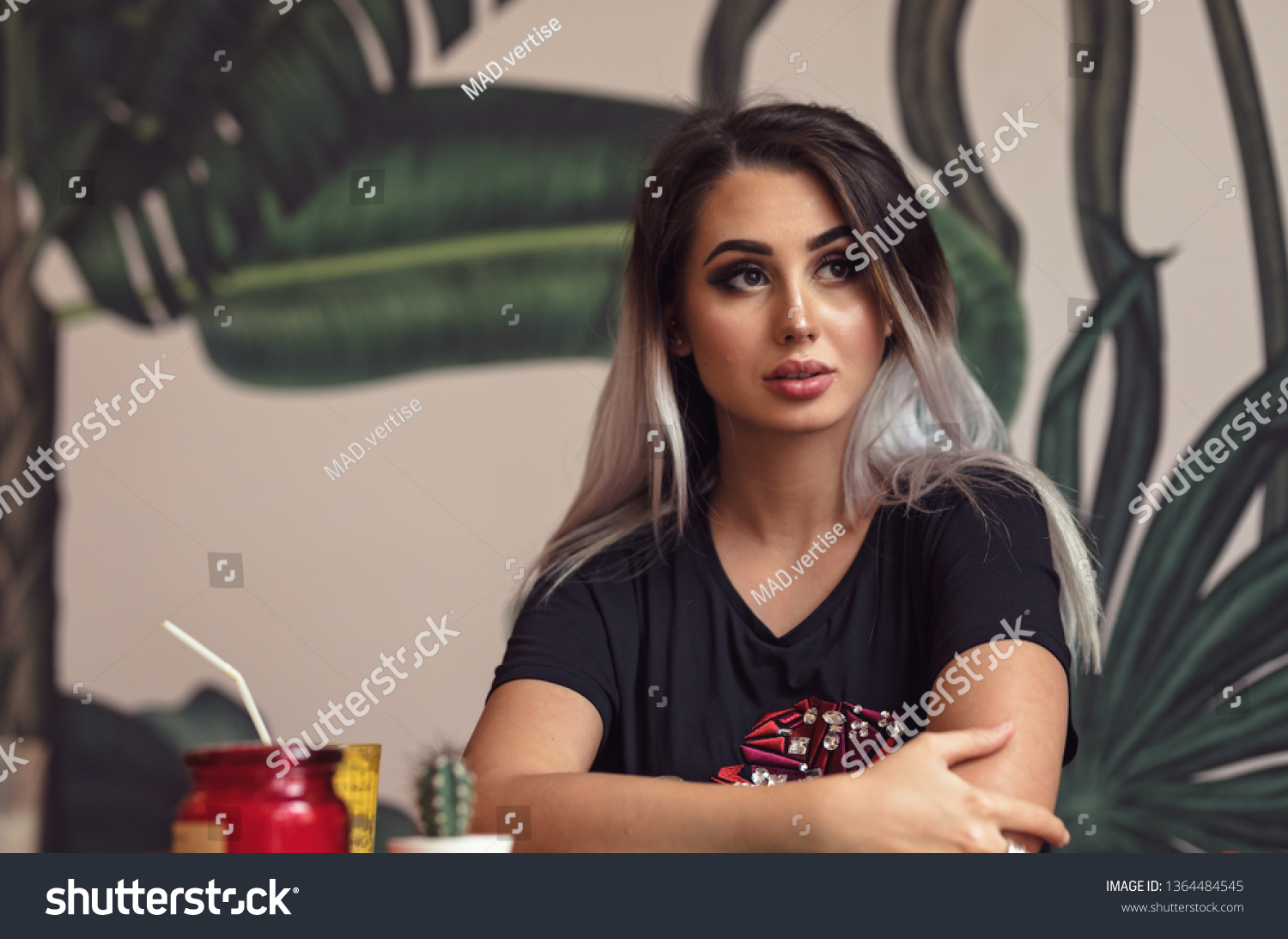 Beautiful girl waiting for best friend in a casual cafe with stylish design drinking orange juice #1364484545