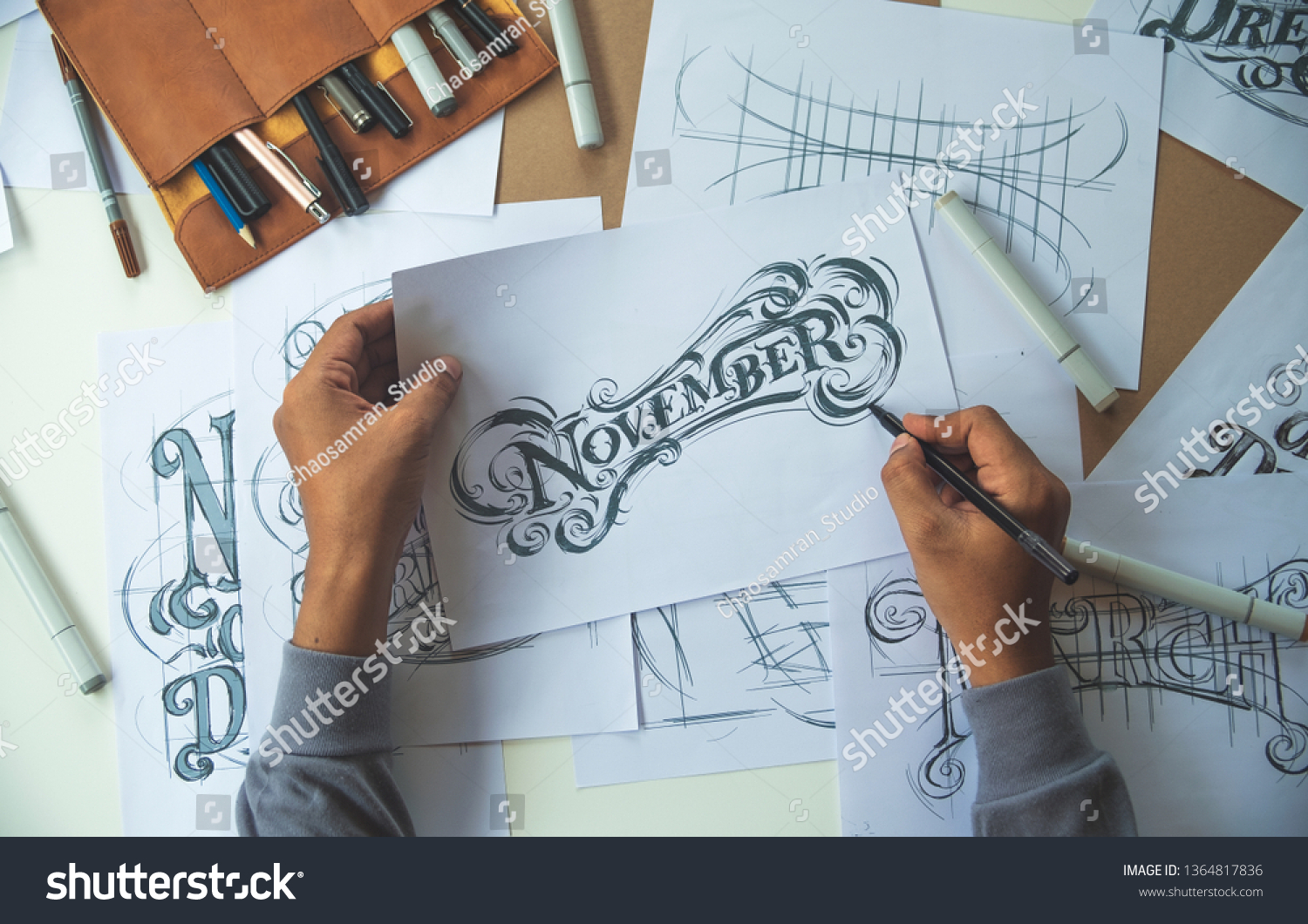 Typography Calligraphy artist designer drawing sketch writes letting spelled pen brush ink paper table artwork.Workplace design studio. #1364817836