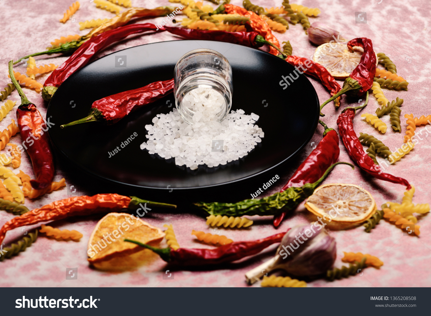 delicious colorful Italian pasta, spice in jar and chili pepper on ceramic plate, orange, garlic on pink textured background, side view #1365208508