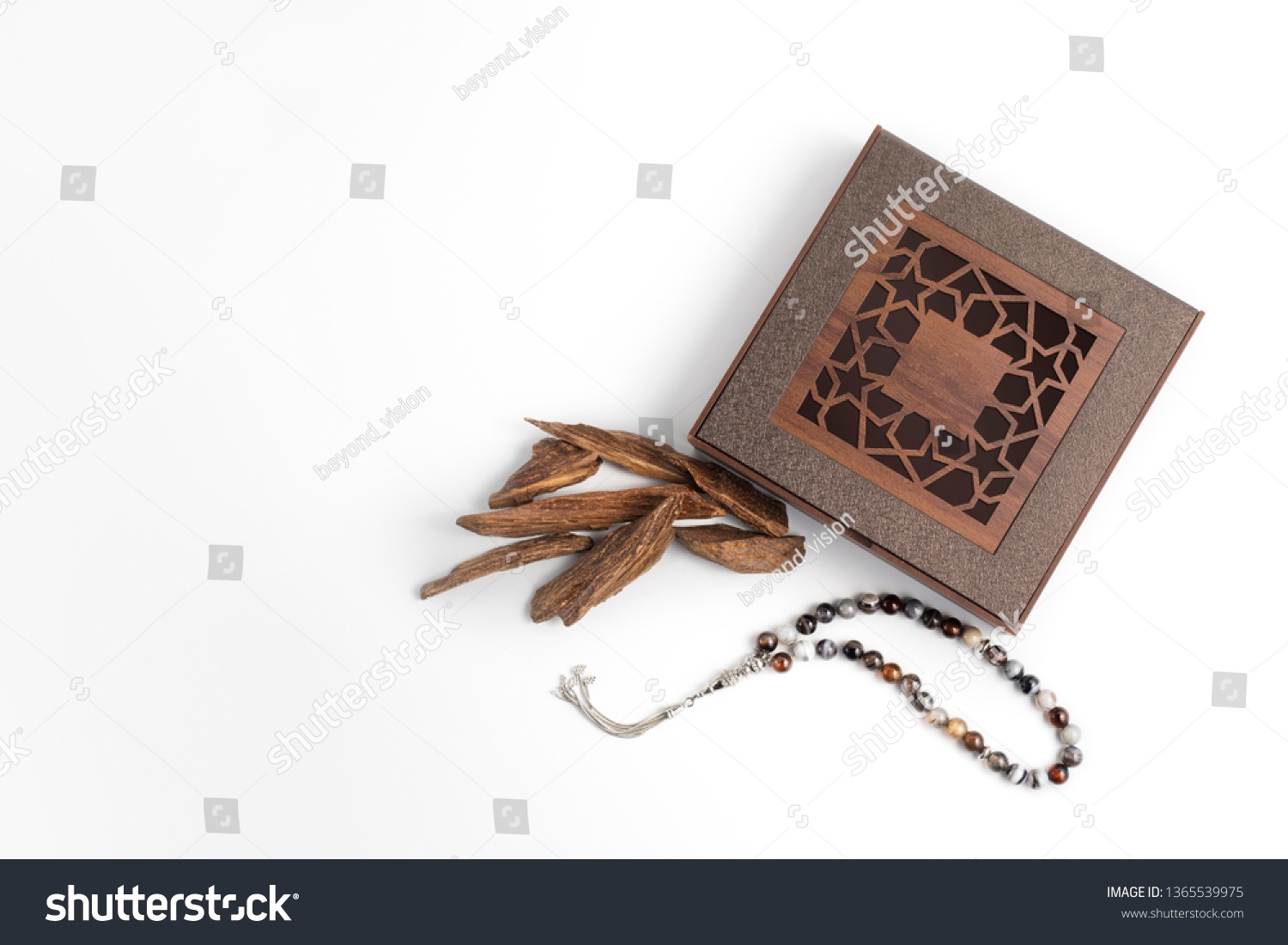 incense Chips, Agarwood, placed near wooden arabesque box with rosary beads isolated on white surface, it's name in Arabic Oud Wood used to incense Cloths, furniture and places for occasions  #1365539975