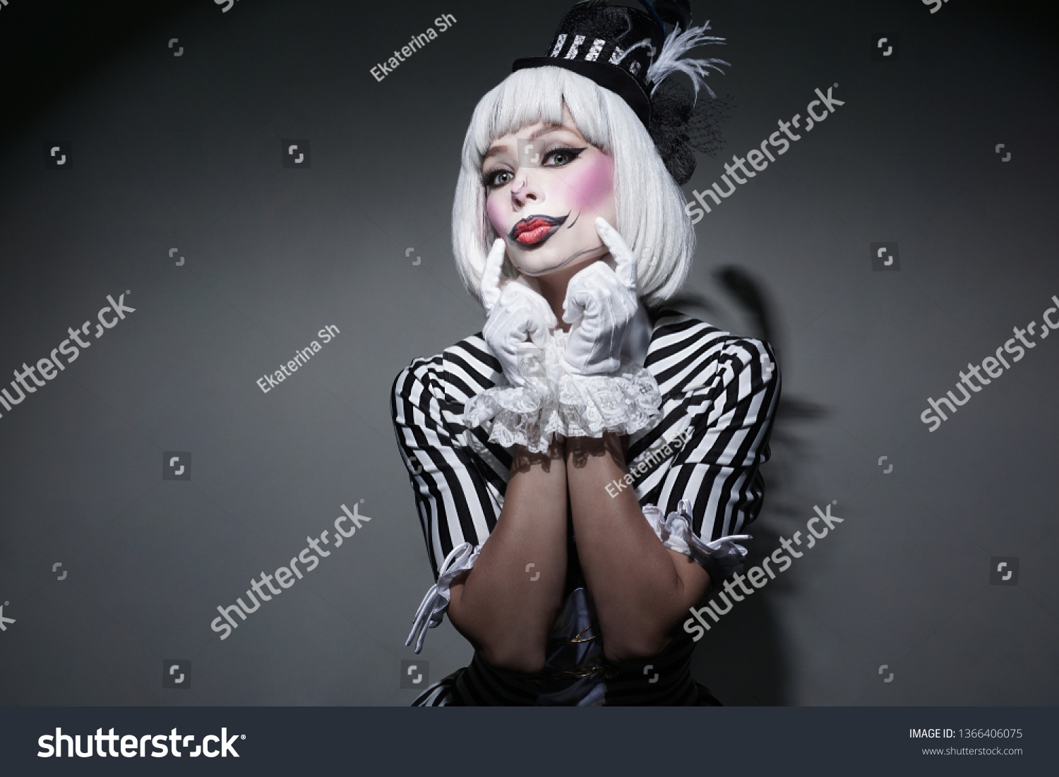 Girl in costume for Halloween holding.Sexy female in dress on gray background. Happy Halloween on the World. Holiday clown. #1366406075