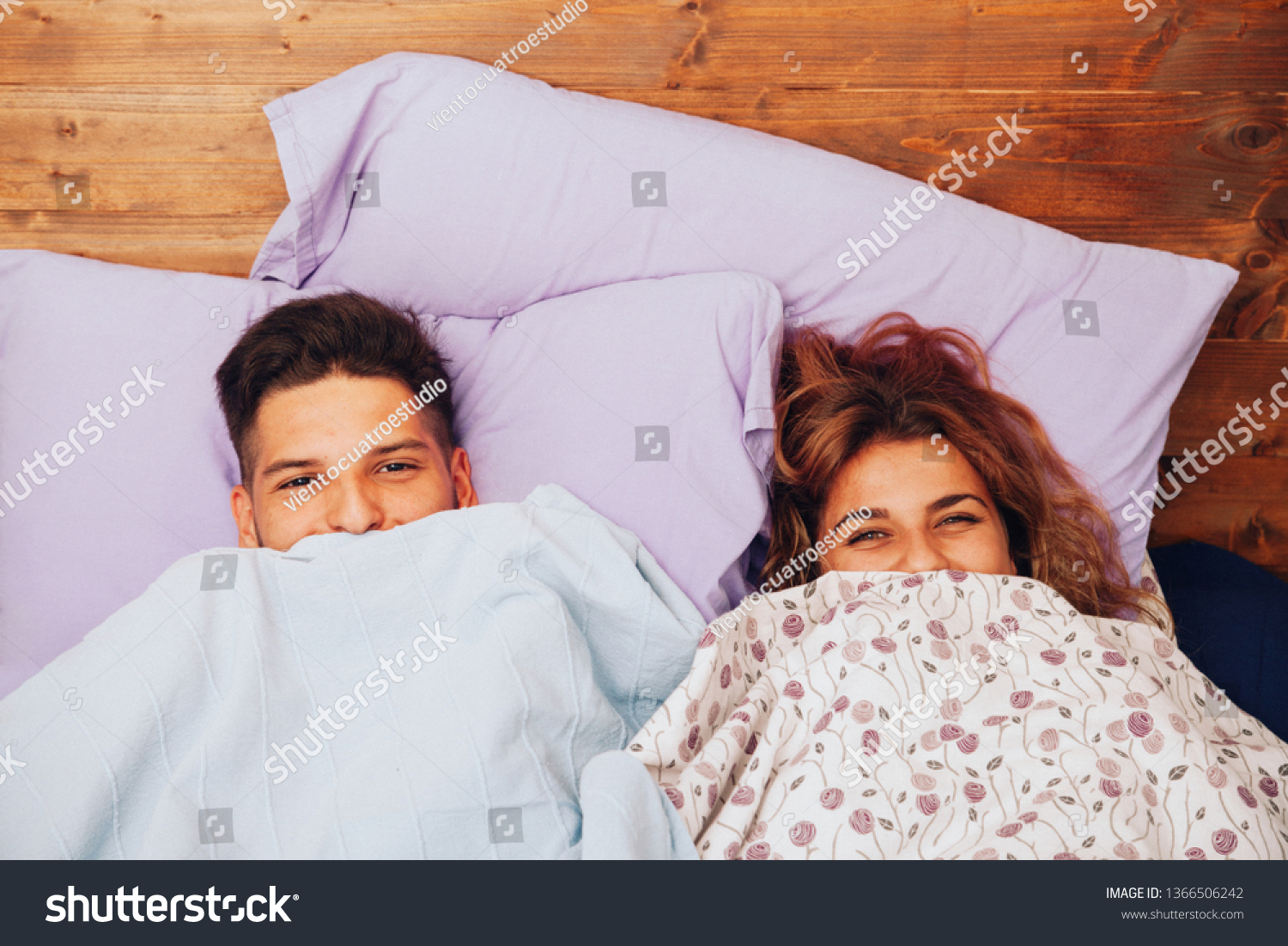 Young smiling heterosexual couple lying down together on the bed #1366506242