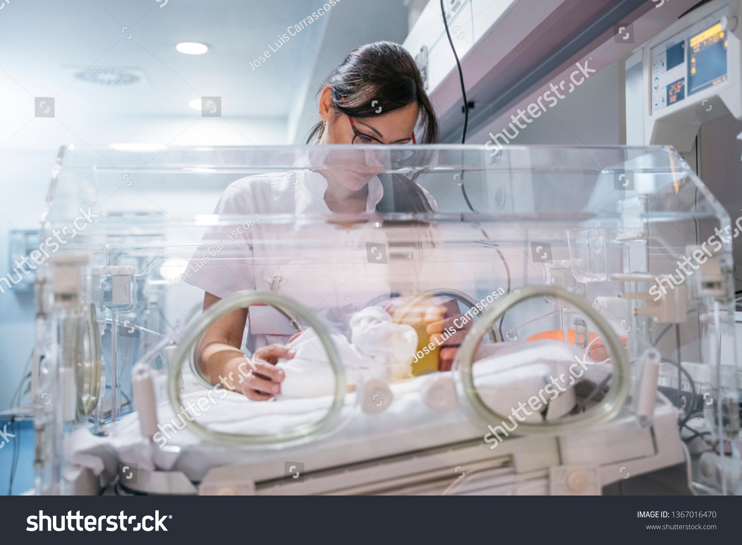 Female doctor examining newborn baby in incubator. Night shift #1367016470