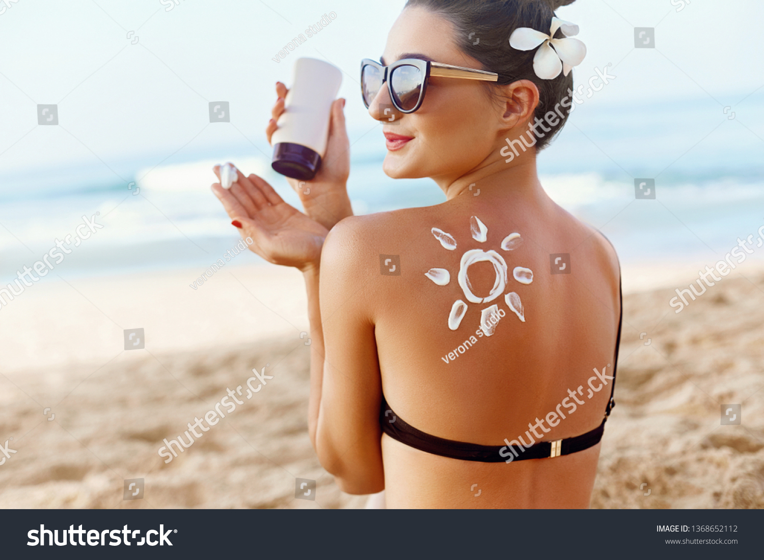 Skin care. Sun protection. Woman apply sun cream. Girl Holding Moisturizing Sunblock. Woman With Suntan Lotion On Beach In Form Of The Sun. Portrait Of Female With  Drawn Sun On A Shoulder. Suncream. #1368652112