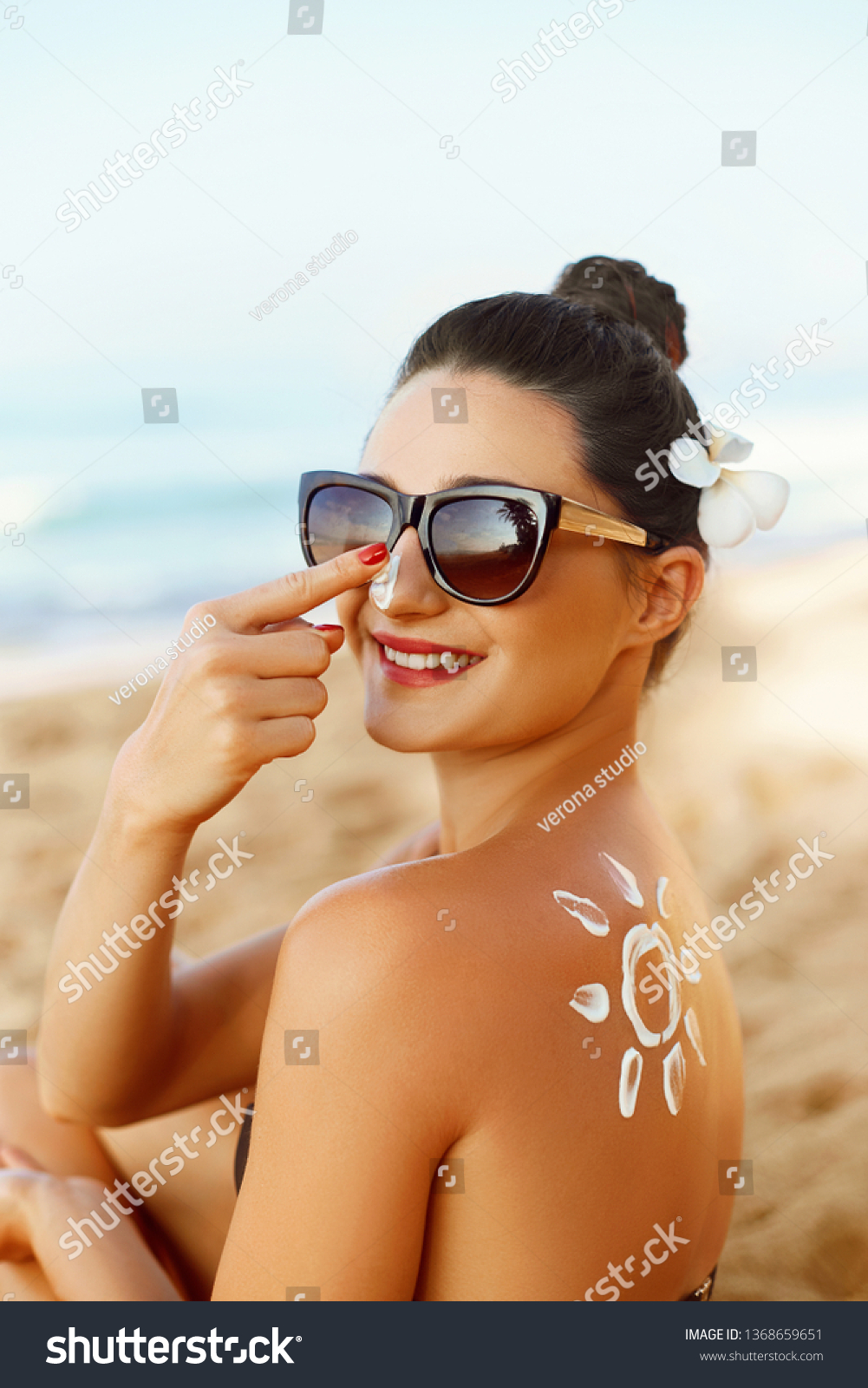 Suntan Lotion. Sexy Young Woman in Bikini  Applying Sunscreen Solar Cream.Sun Protection. Sun Cream. Skin and Body Care.Girl Holding Moisturizing Sunblock. Sun shape on the shoulder. Skin Protection #1368659651
