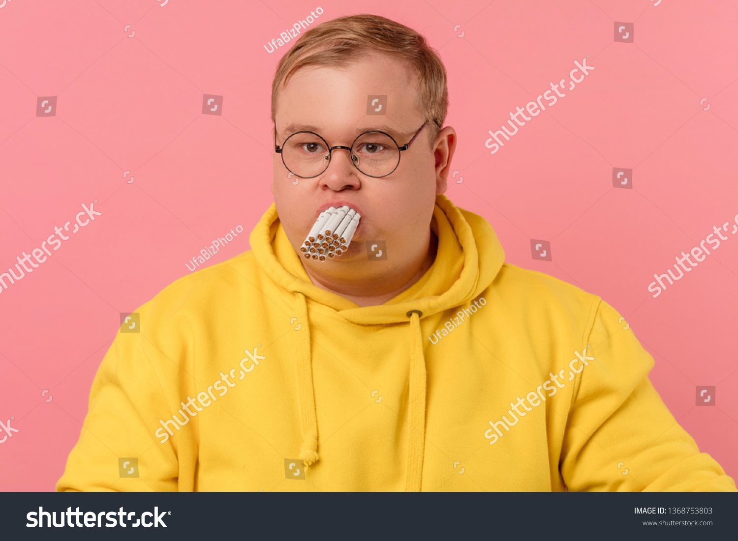 Stressed corpulent man trying to smoke a whole pile of cigarettes simultaneously, killing his lungs. Stop smoking concept, unhealthy bad habits and addictions. Harmful Smoking Concept #1368753803