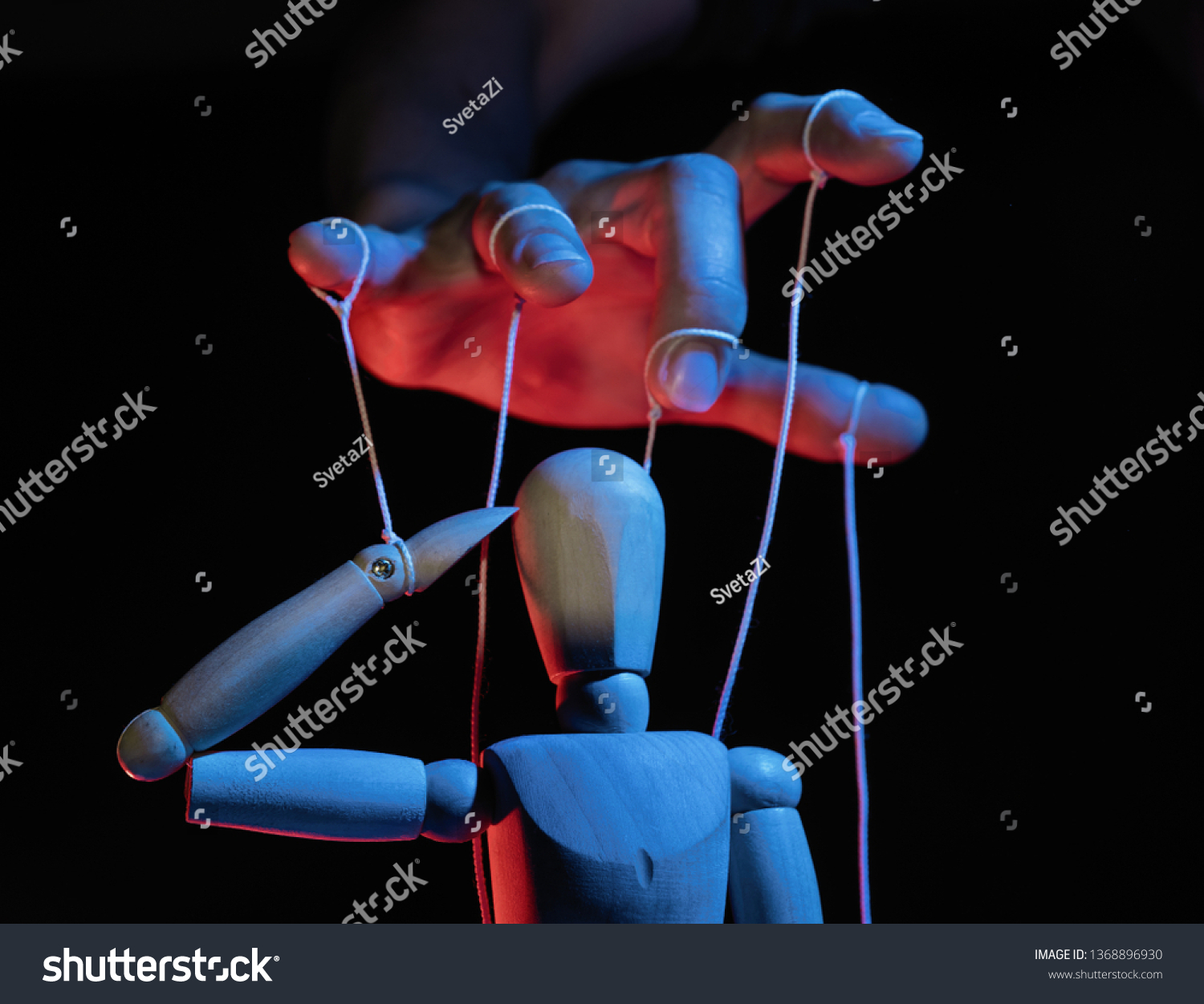 Concept of control. Marionette in human hand. Objects are colored on red and blue light. #1368896930