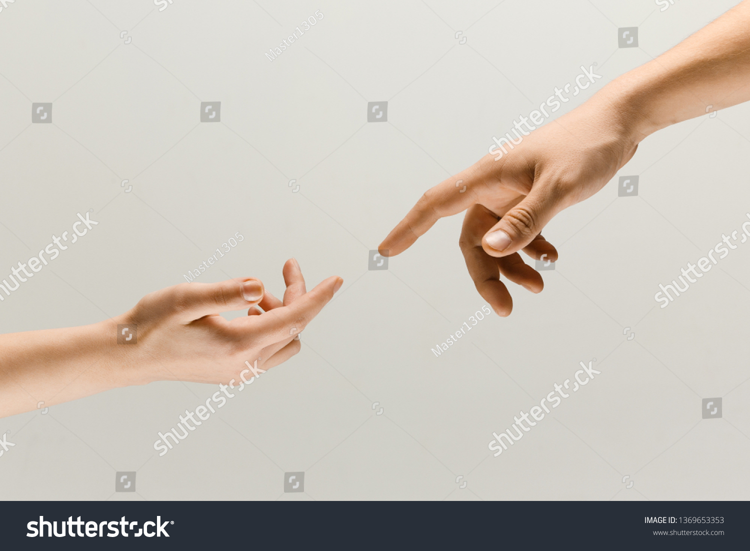 Moment of weightless. Two male hands trying to touch like a creation of Adam sign isolated on grey studio background. Concept of human relation, community, togetherness, symbolism, culture and history #1369653353