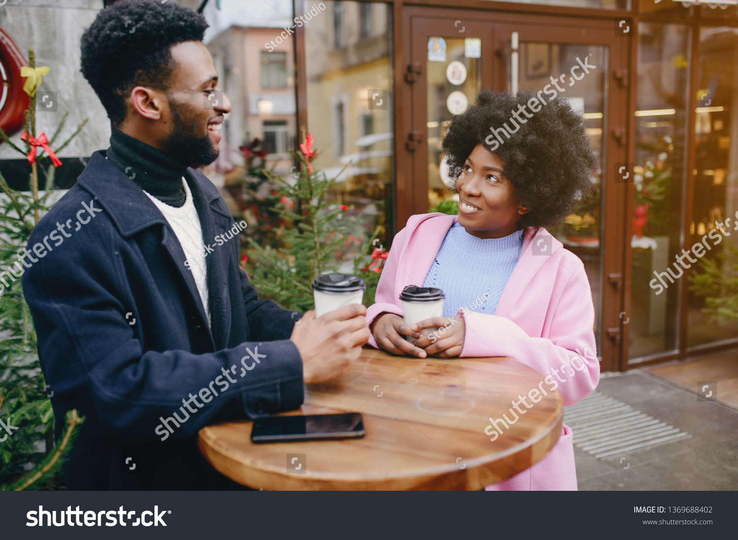 Cute black couple have fun in a city. Beautiful black girl in a pink coat. Man in a black coat. Couple with coffee #1369688402