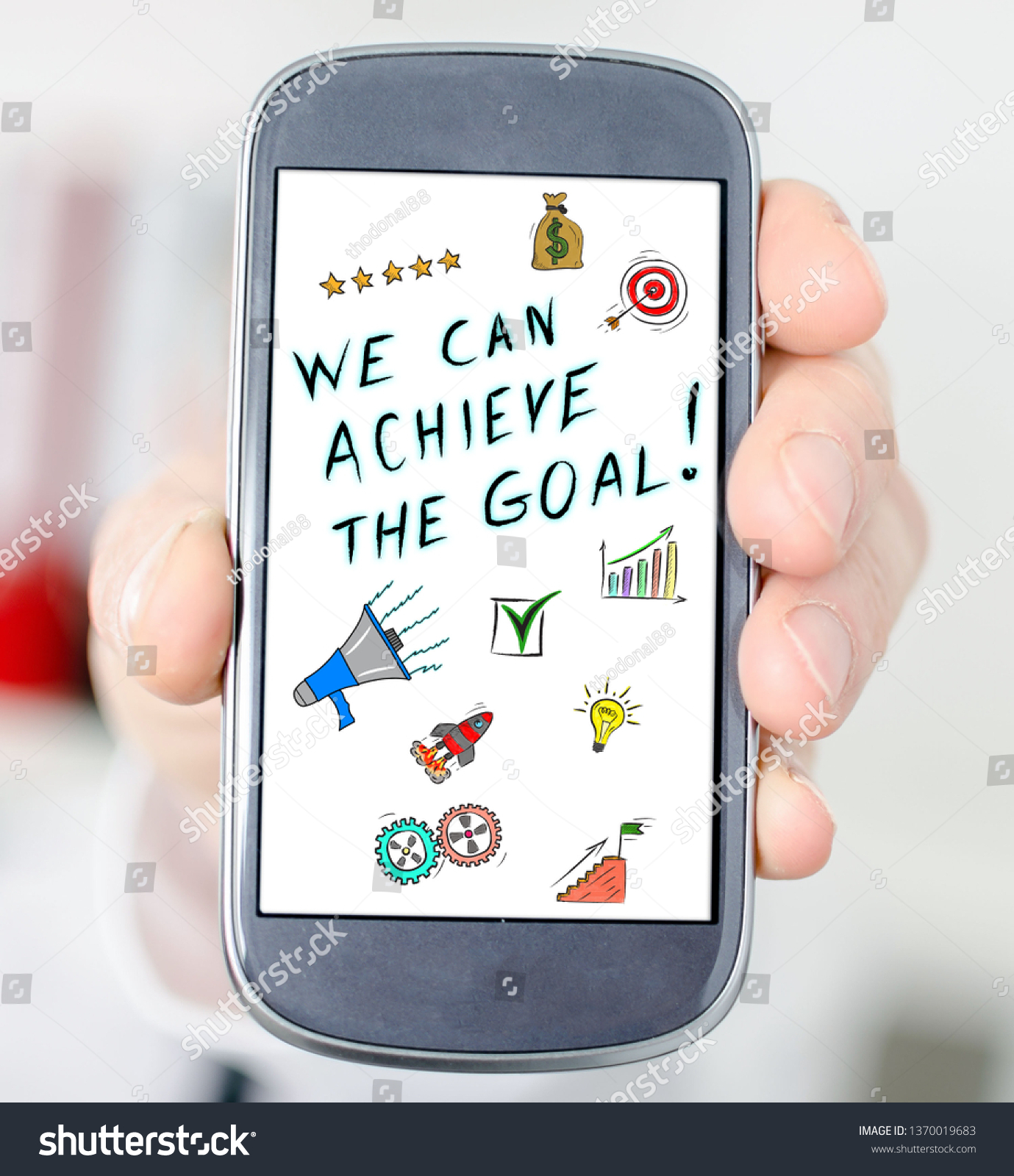 Hand holding a smartphone with goal achievement concept #1370019683