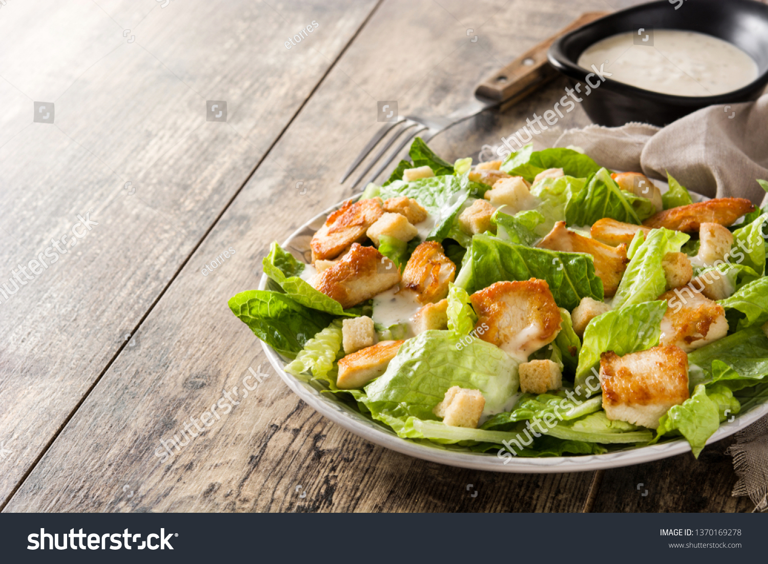 Caesar salad with lettuce,chicken and croutons on wooden table. Copyspace #1370169278