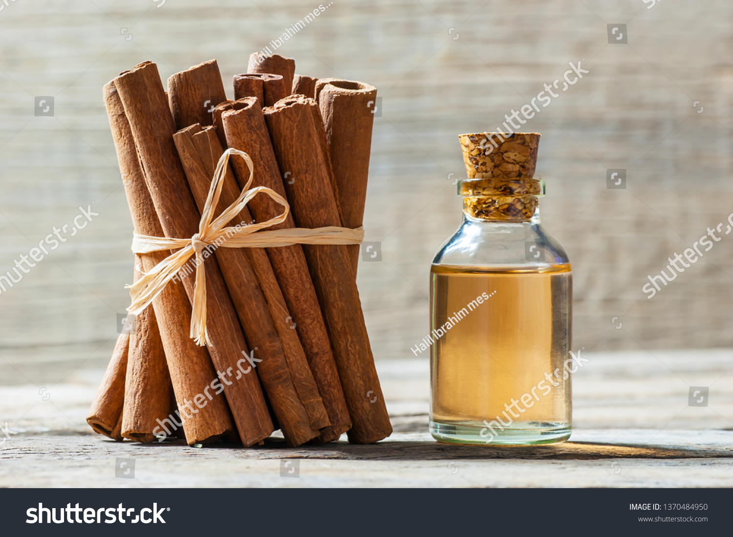 Close up bottle of cinnamon oil with cinnamon sticks and cinnamon powder on wooden background, healthy spice concept Cinnamomum verum
 #1370484950