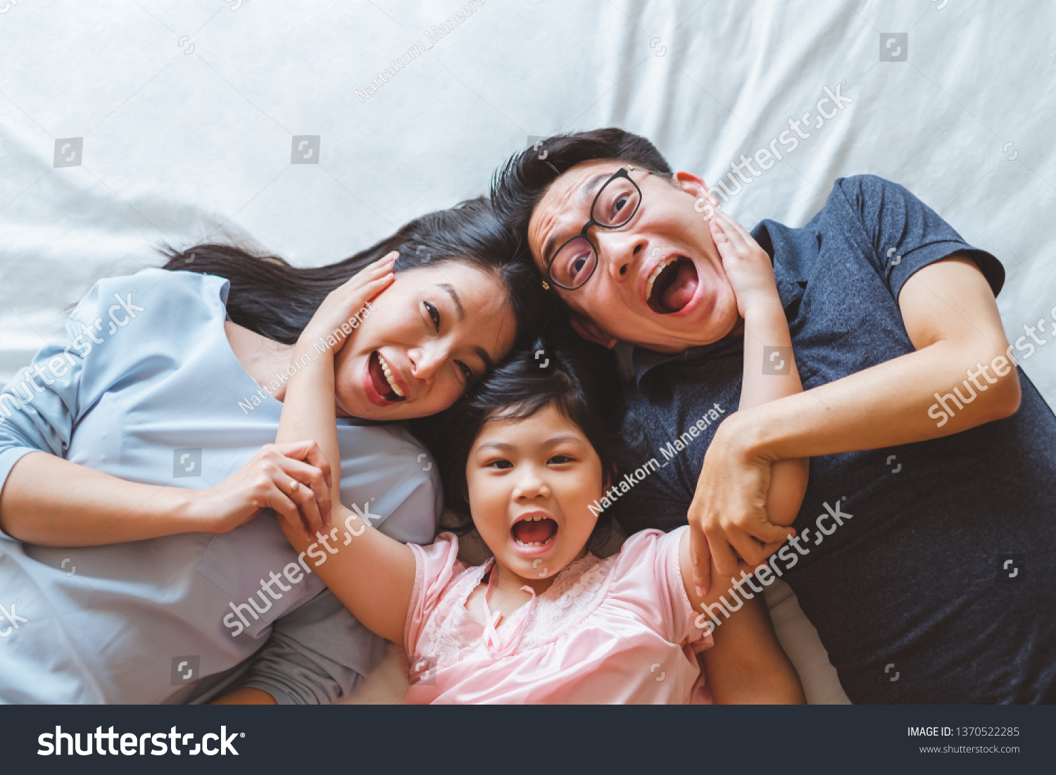 Happy Asian family laying on bed in bedroom with happy and smile, top view #1370522285