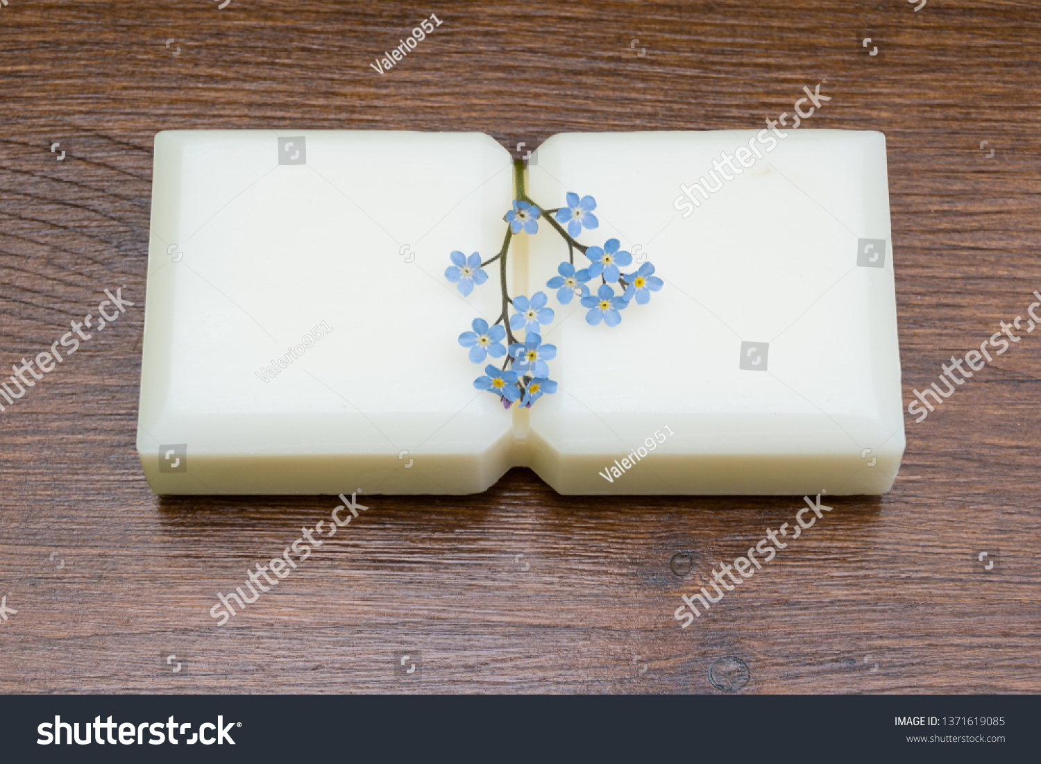 Small marseille soap isolated with flowers on wooden table in the foreground.foreground. #1371619085