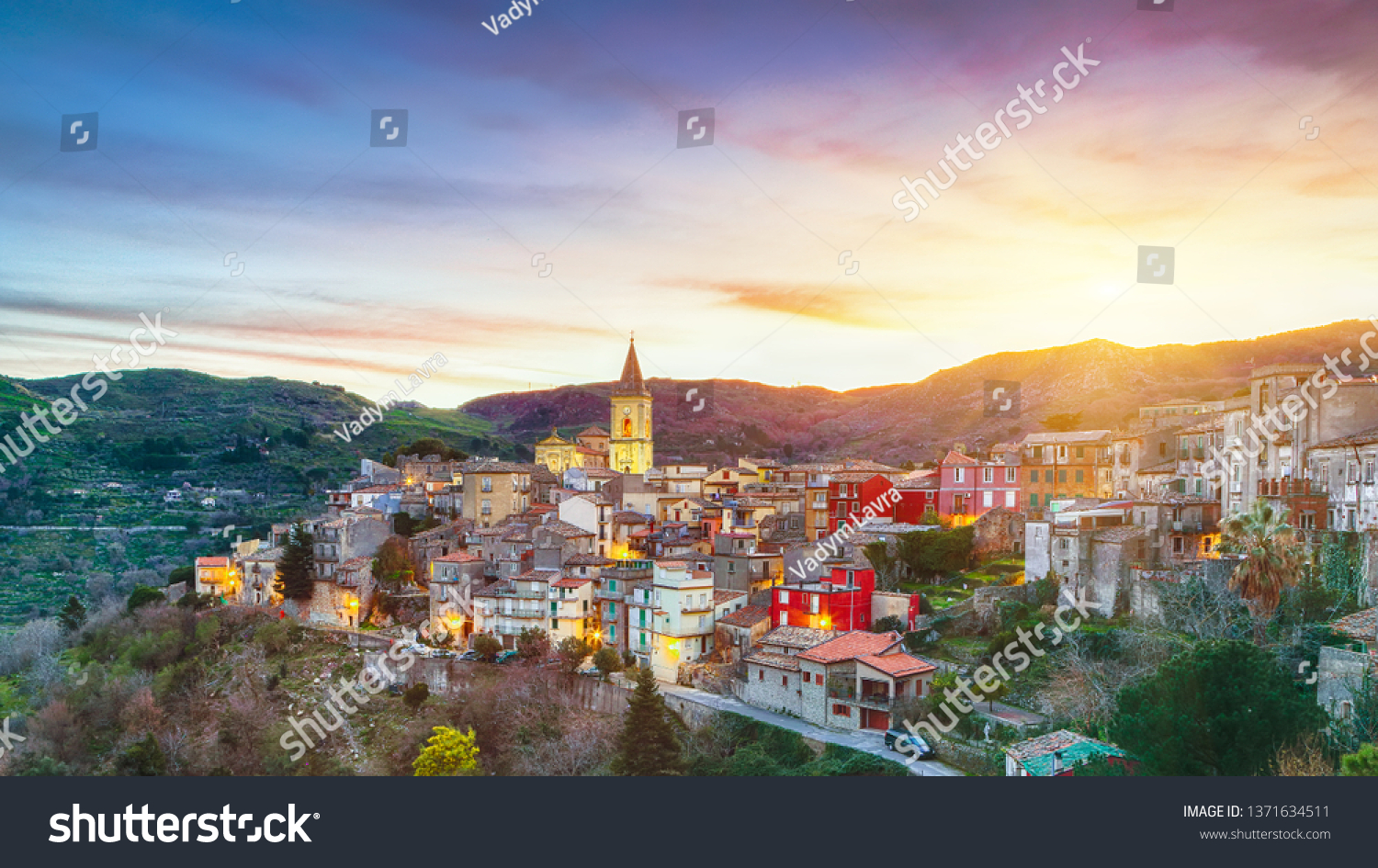 Panorama of the belltower and the village in the valley at early sunrise. Mountain village Novara di Sicilia, Sicily, Italy #1371634511