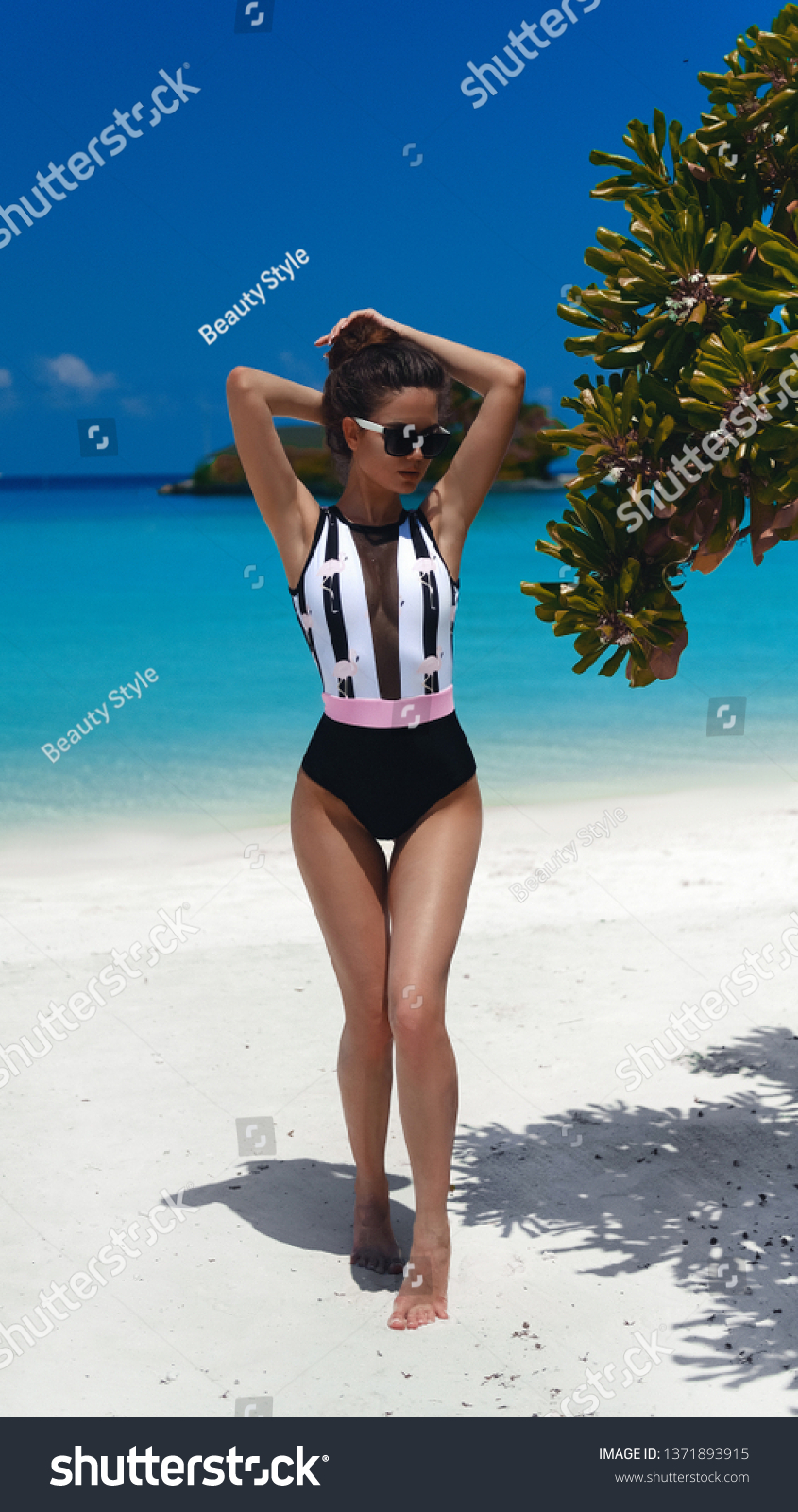 Summer vacation. Fashionable Woman in bikini suntanning on tropical beach. Slim girl posing on exotic island by beautiful turquoise ocean. Brunette model in trendy swimwear resting in Maldives lagoon. #1371893915