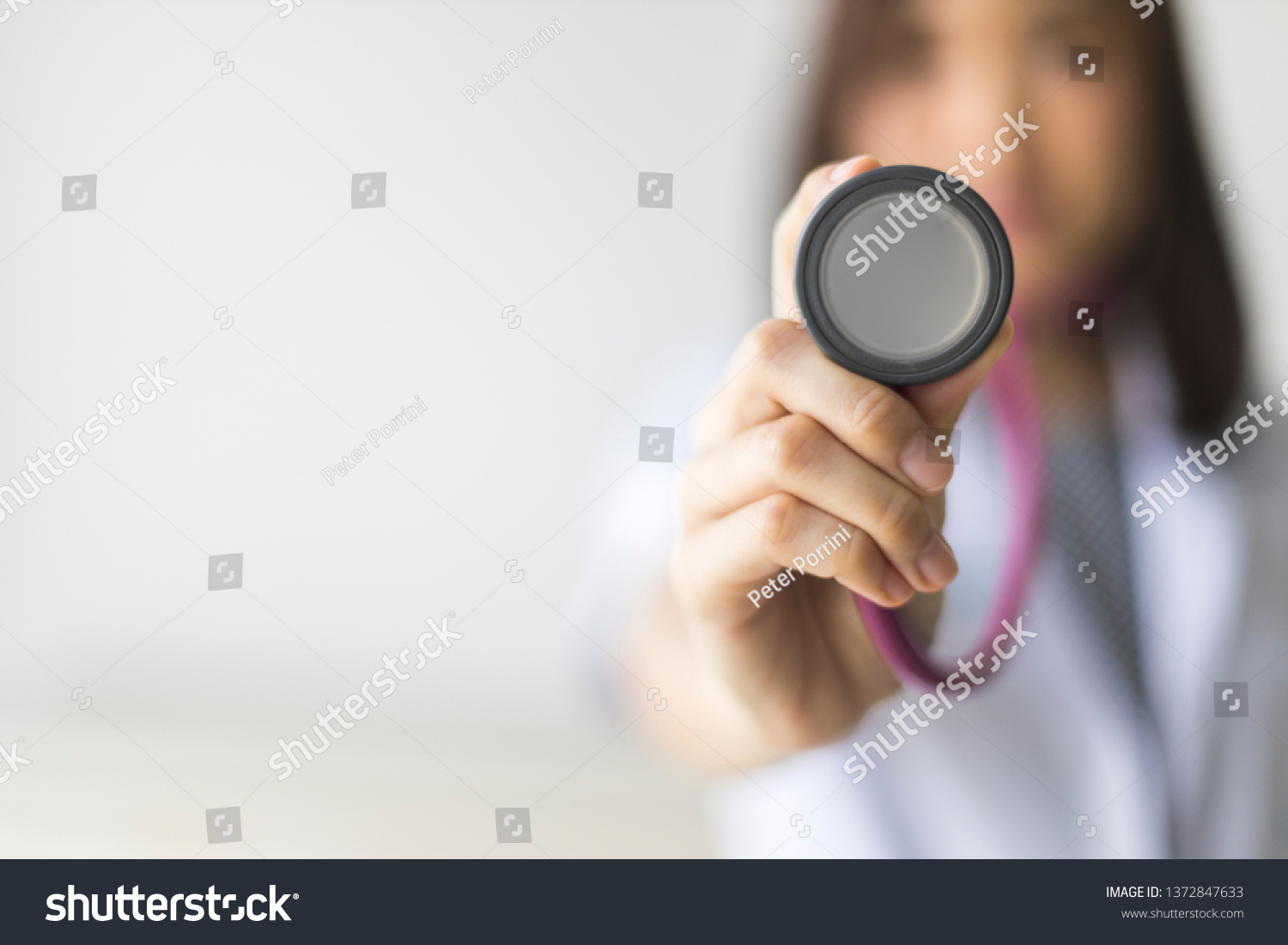 Asian woman doctor smiling and holding the pink stethoscope. Selective focus at stethoscope and intention to blurred background. Pediatric doctor with smile. Medical and Insurance concept. #1372847633