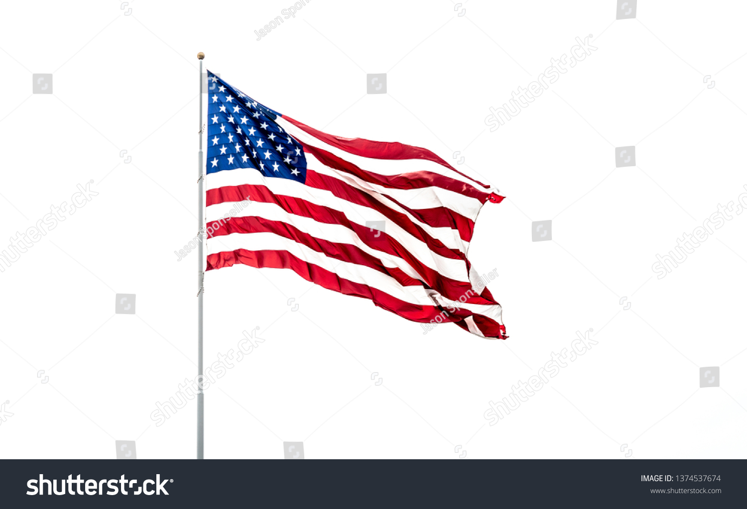 Isolated USA Flag with stars and stripes waving in wind on flag pole against white background. #1374537674