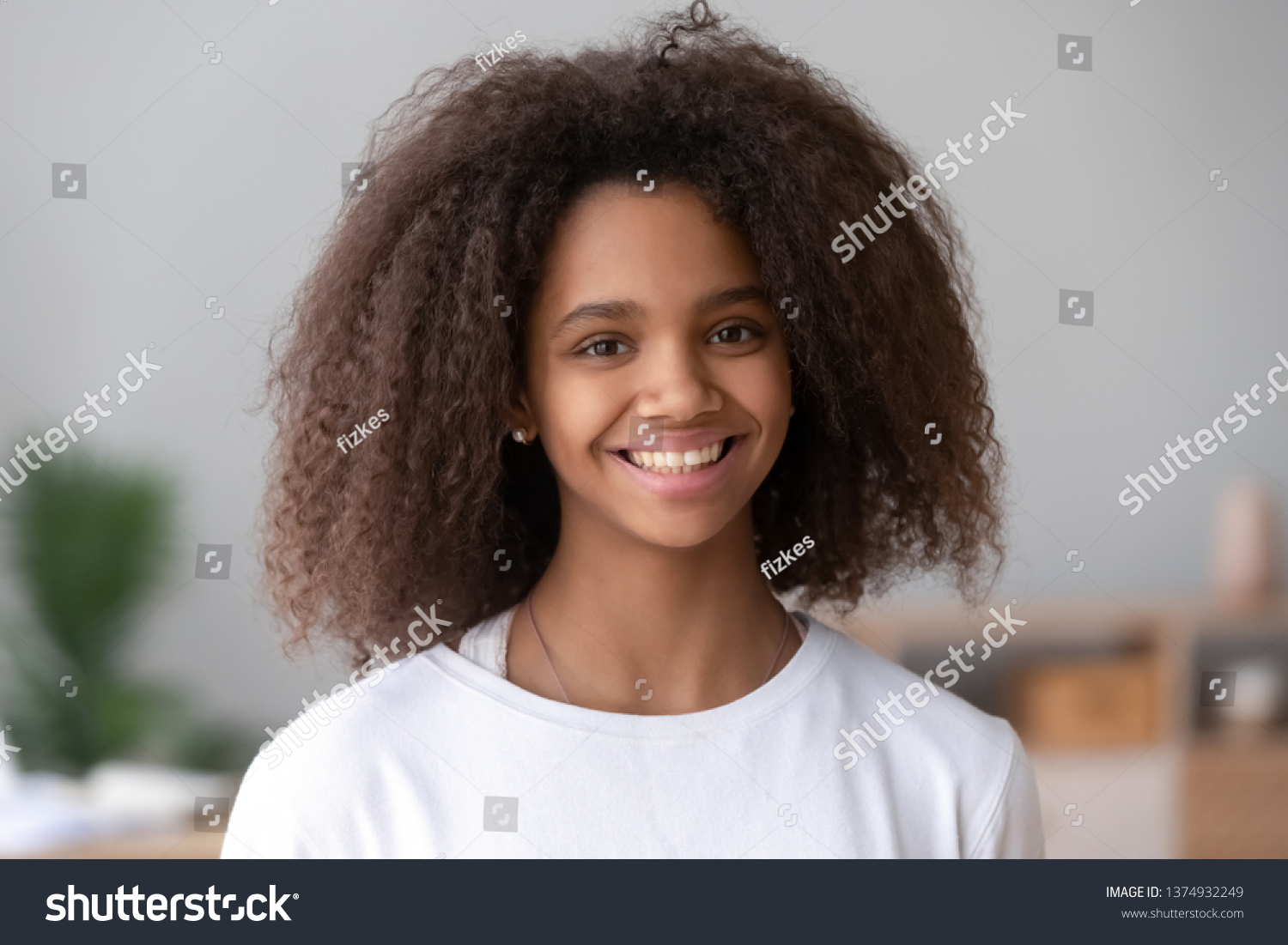 Head shot portrait of smiling African American teenage girl, feeling happy, posing for photo at home, beautiful positive mixed race teenager looking at camera, laughing, having fun #1374932249