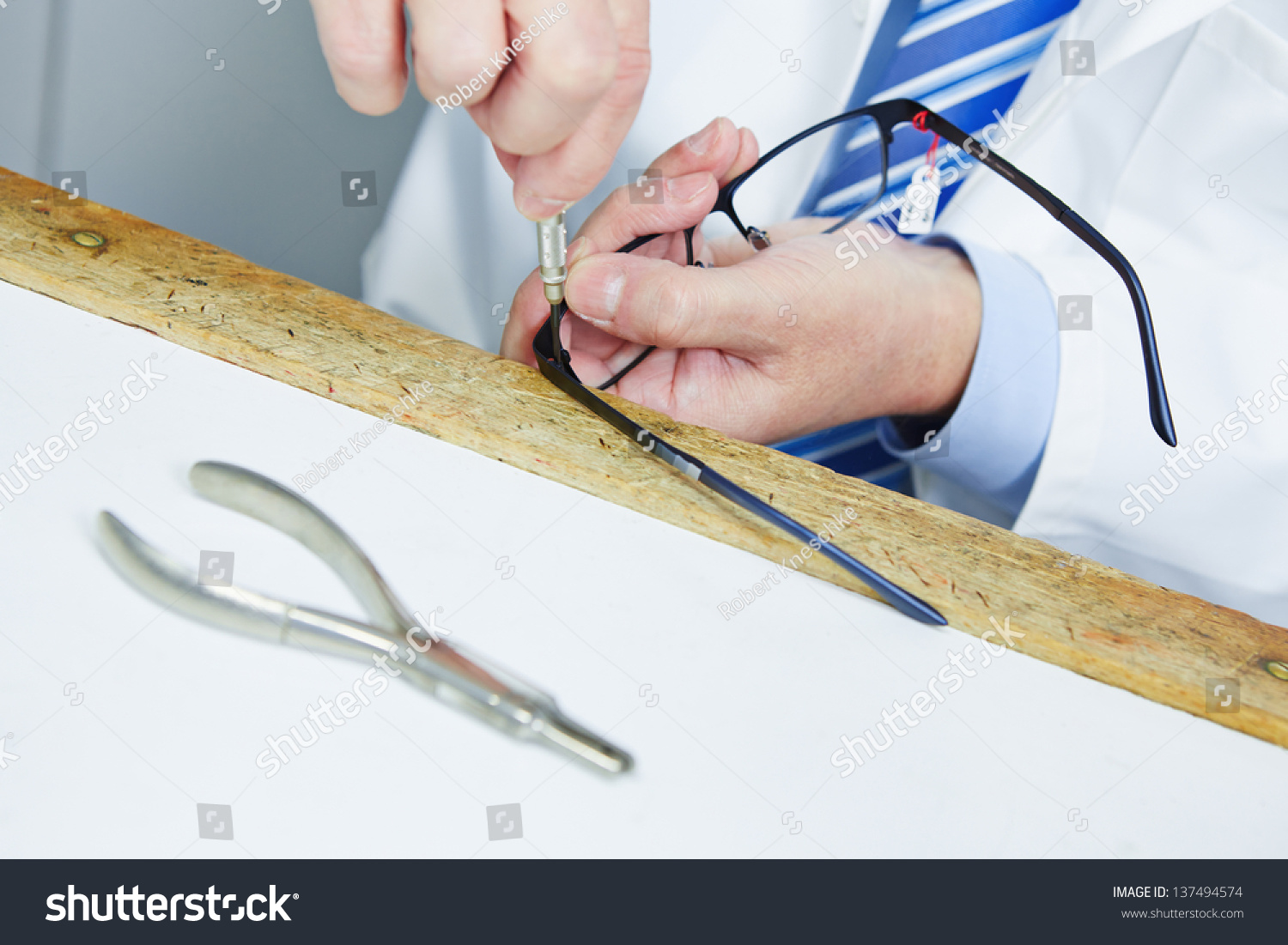 Optician fixing hinge of glasses with a screwdriver #137494574