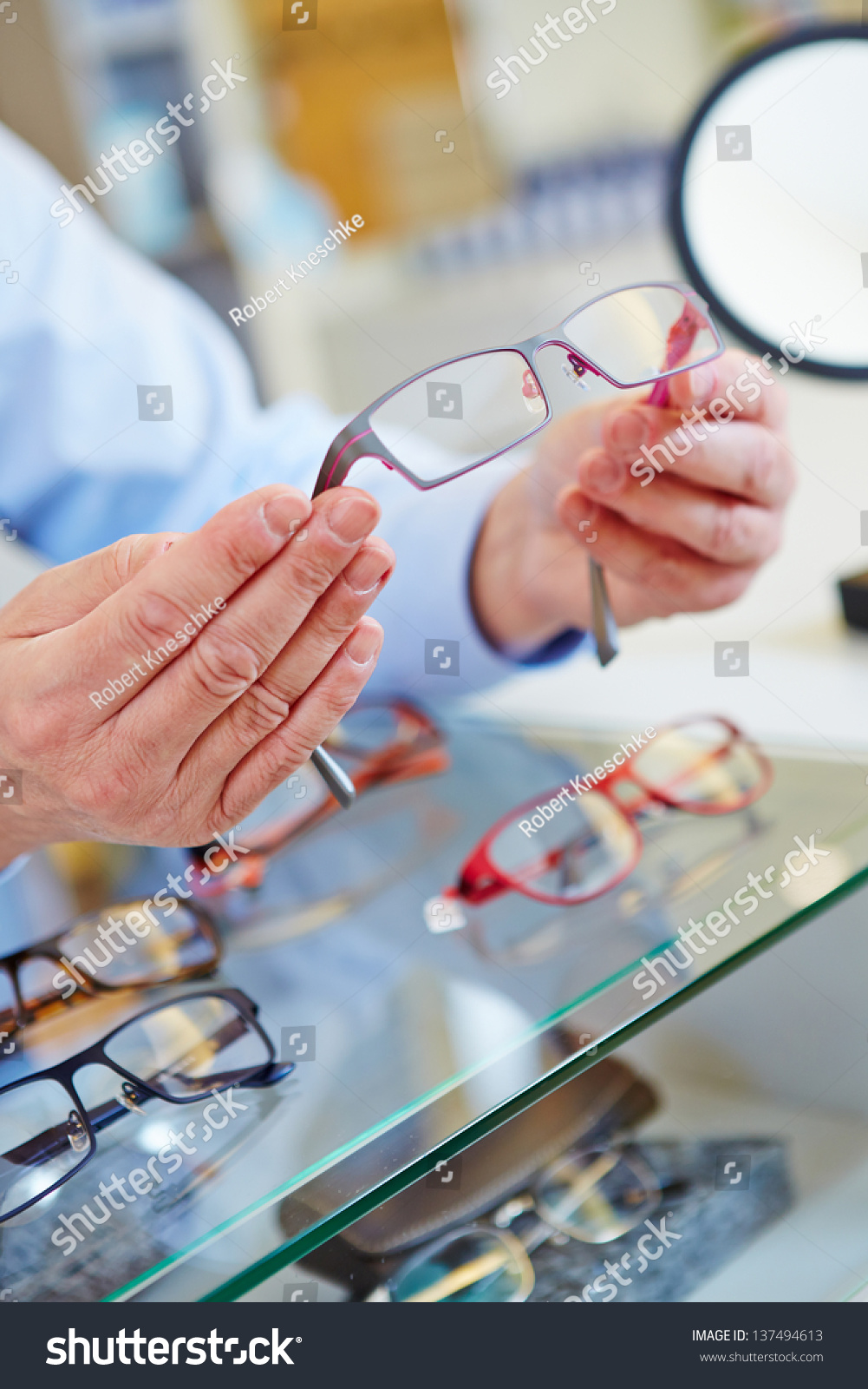 hands of an optician offering new glasses in his retail store #137494613