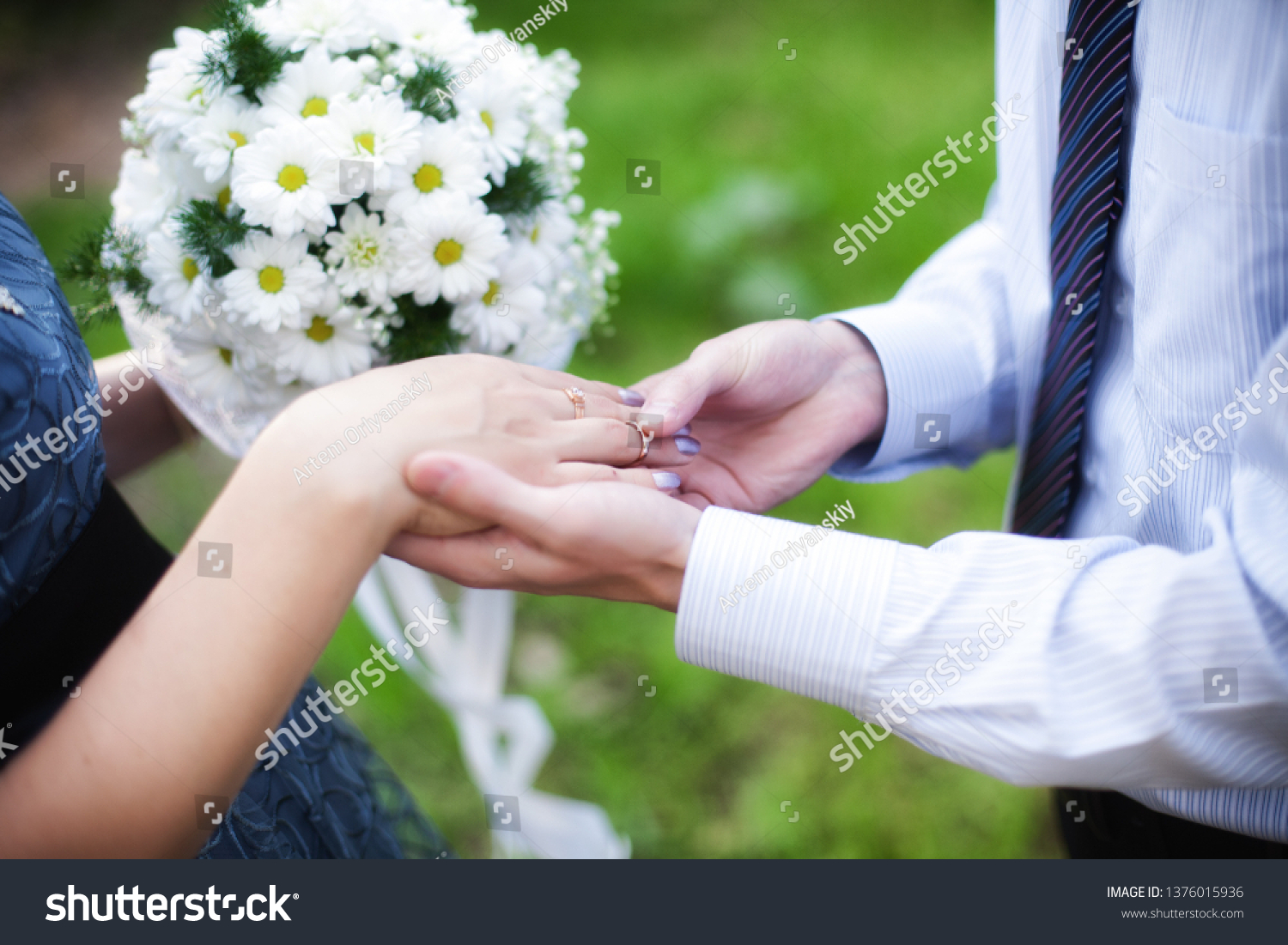 Wedding rings, wedding day. Wedding couple. He put an engagement ring on her. bridegroom puts the ring on the bride in nature. the moment when the groom puts the ring on the bride. #1376015936