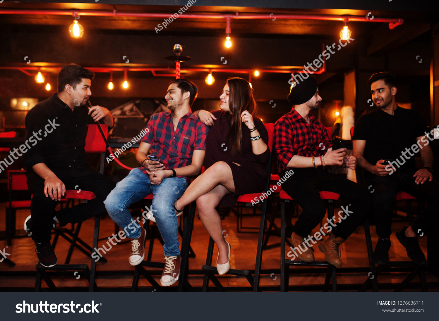Group of indian friends sitting at lounge bar, smoke hookah and having rest. #1376636711