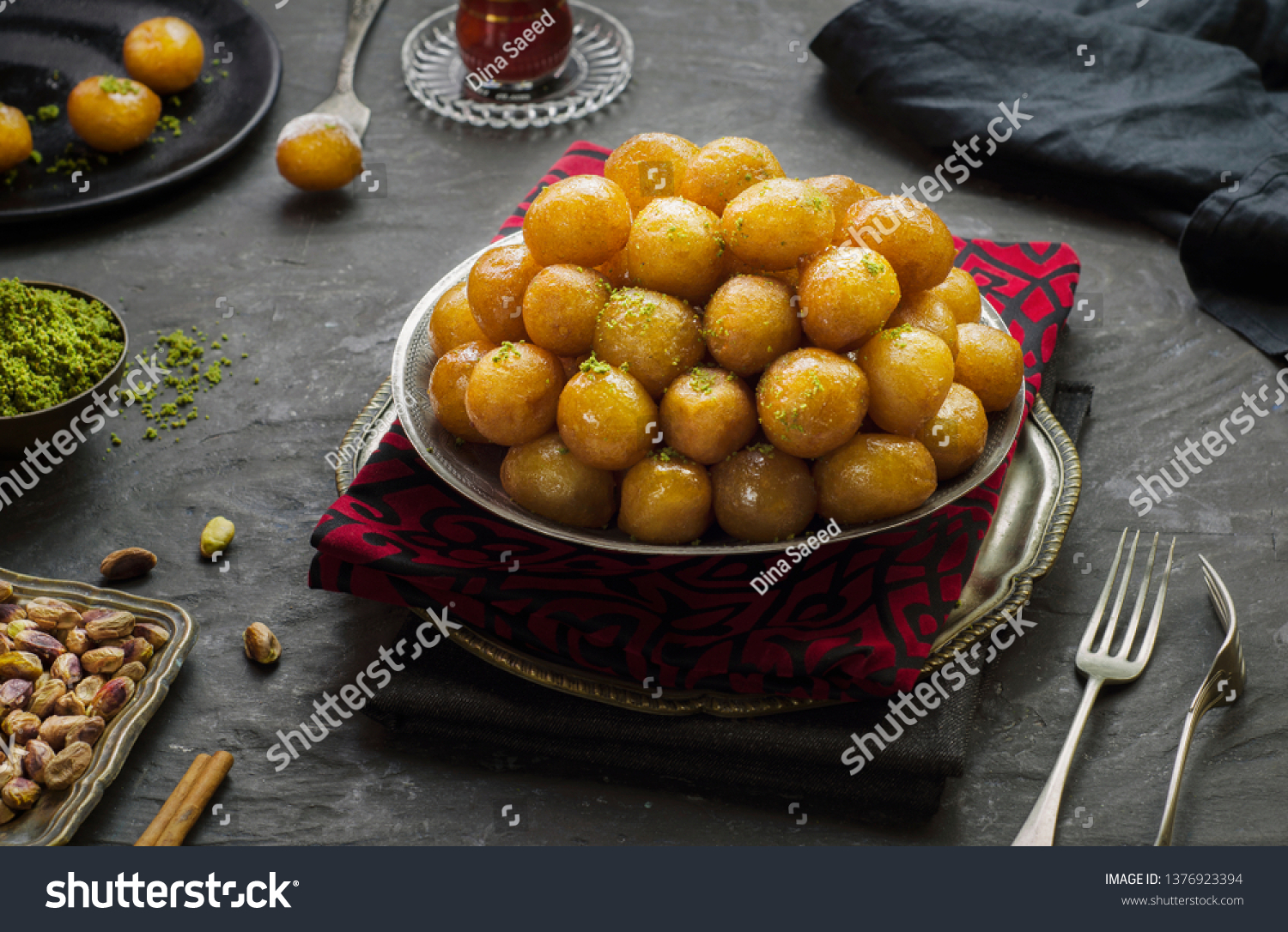 Arabic Cuisine; Middle Eastern traditional dessert/Ramadan dessert "Zalabya", or Luqmat Al-Kadi served with honey, pistachio cinnamon, sugar and oriental tea. Close up with copy space. #1376923394