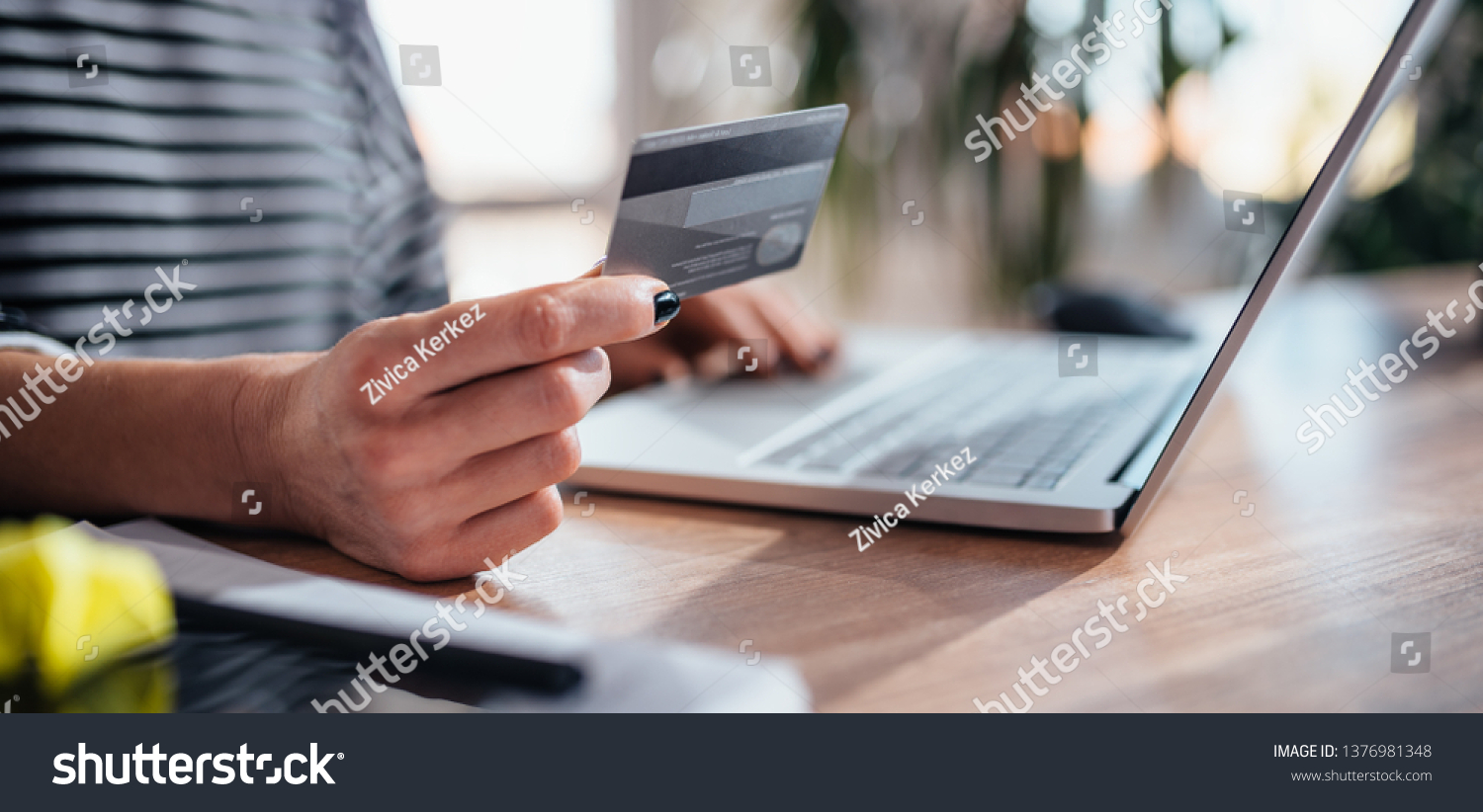 Woman using laptop and shopping online while holding credit card #1376981348