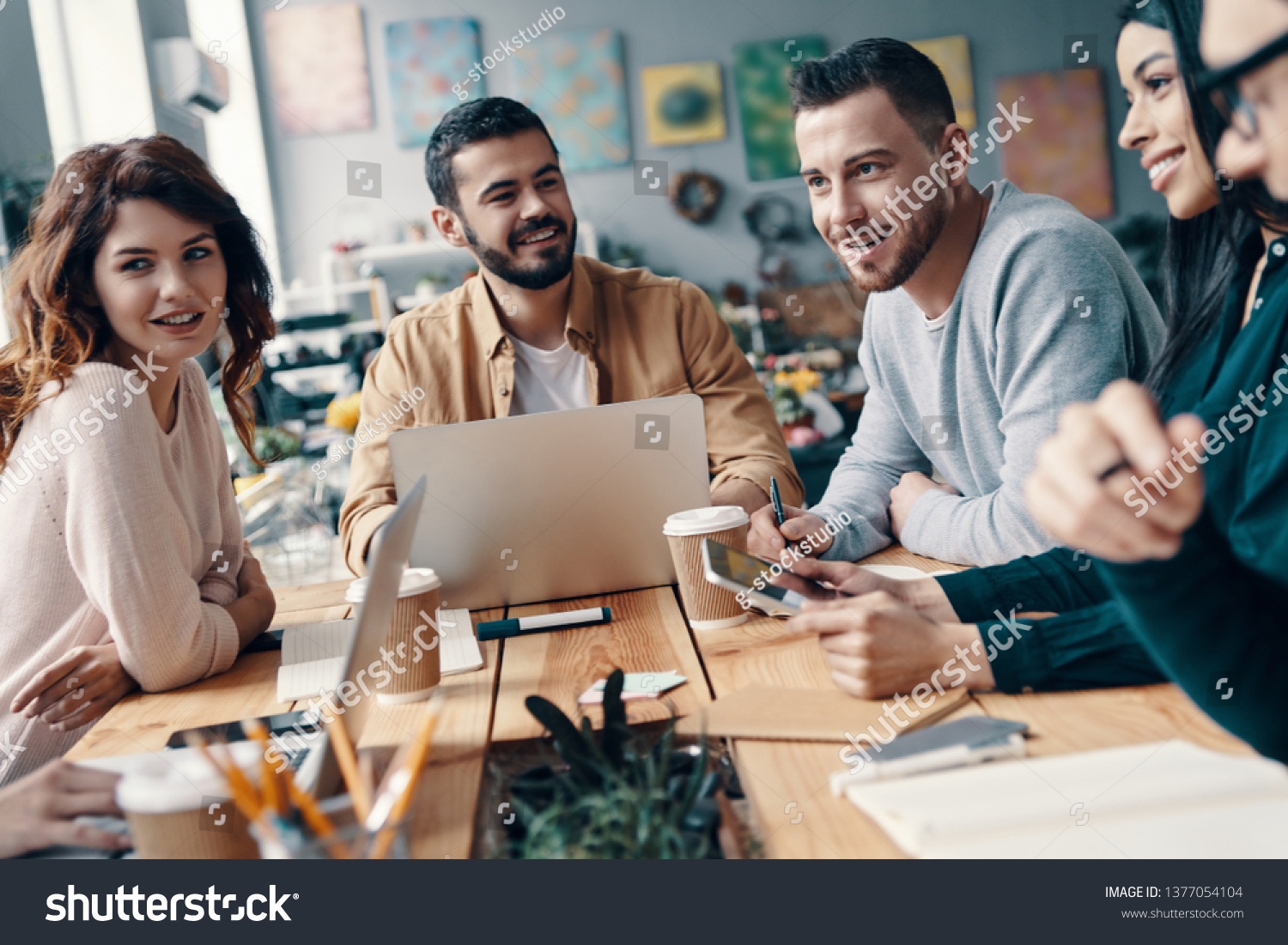 Collaboration. Group of young modern people in smart casual wear discussing something and smiling while working in the creative office   #1377054104