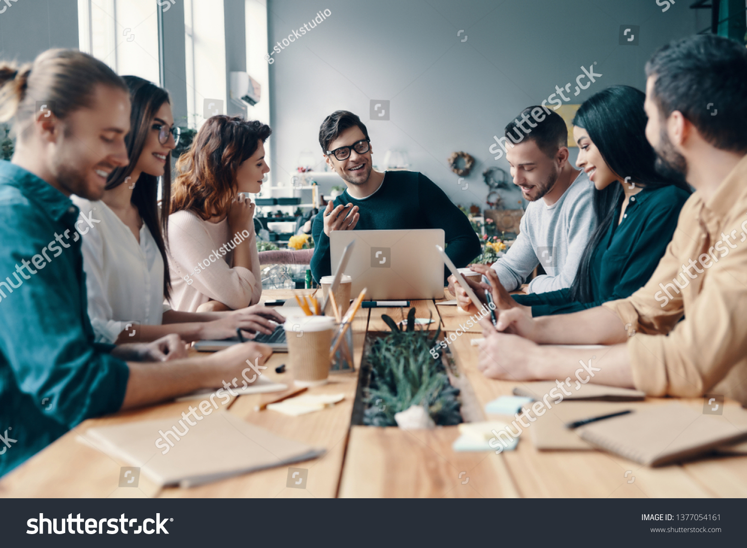 Marketing team. Group of young modern people in smart casual wear discussing something while working in the creative office               #1377054161