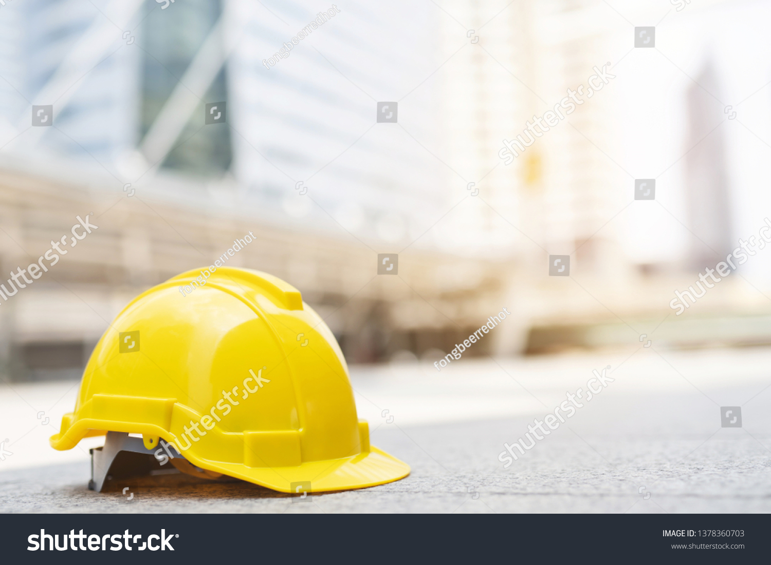 yellow hard safety wear helmet hat in the project at construction site building on concrete floor on city with sunlight. helmet for workman as engineer or worker. concept safety first.  #1378360703