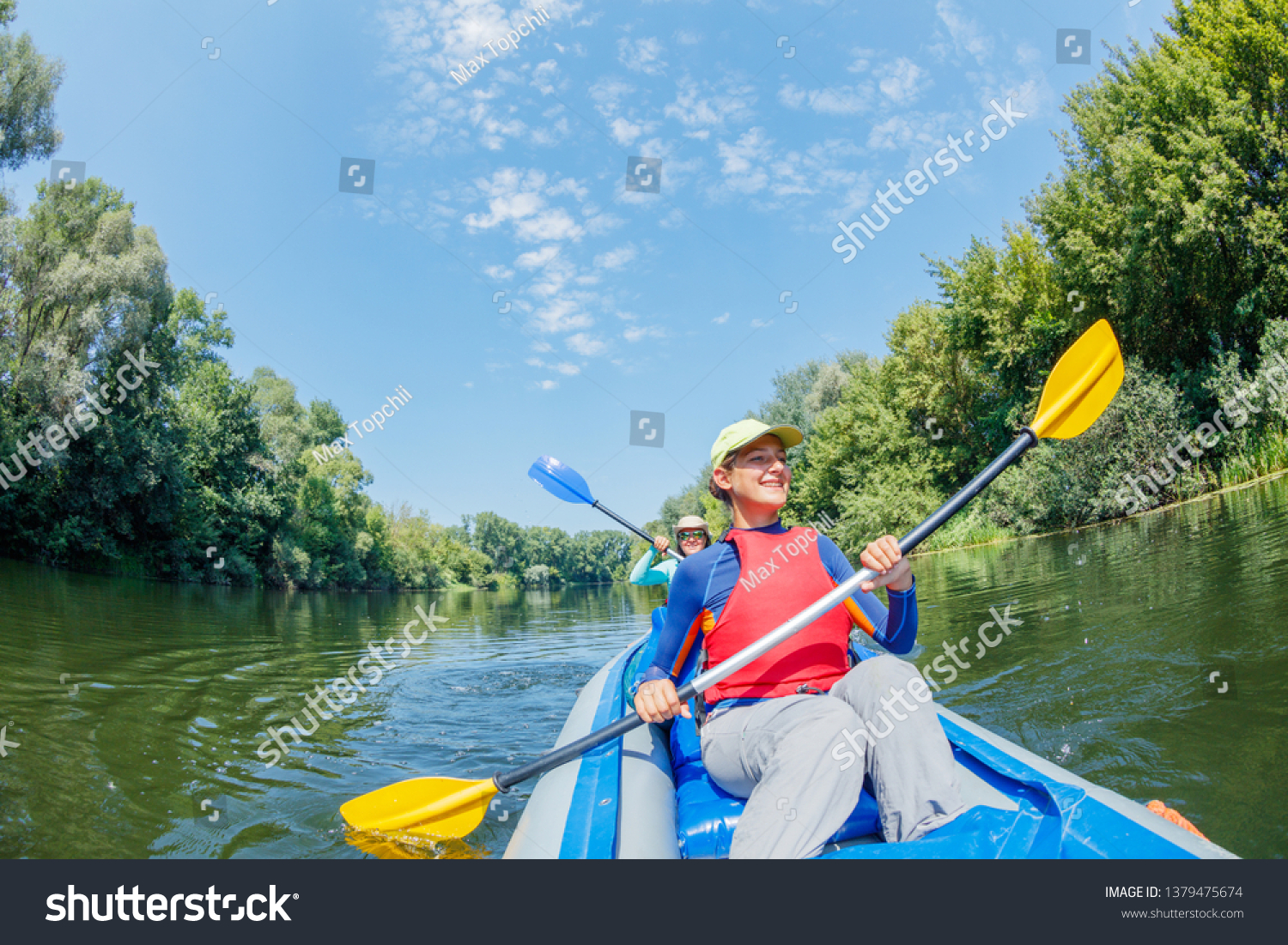 Happy family kayaking on the river. Active girl with her mother having fun enjoying adventurous experience with kayak on a sunny day during summer vacation #1379475674