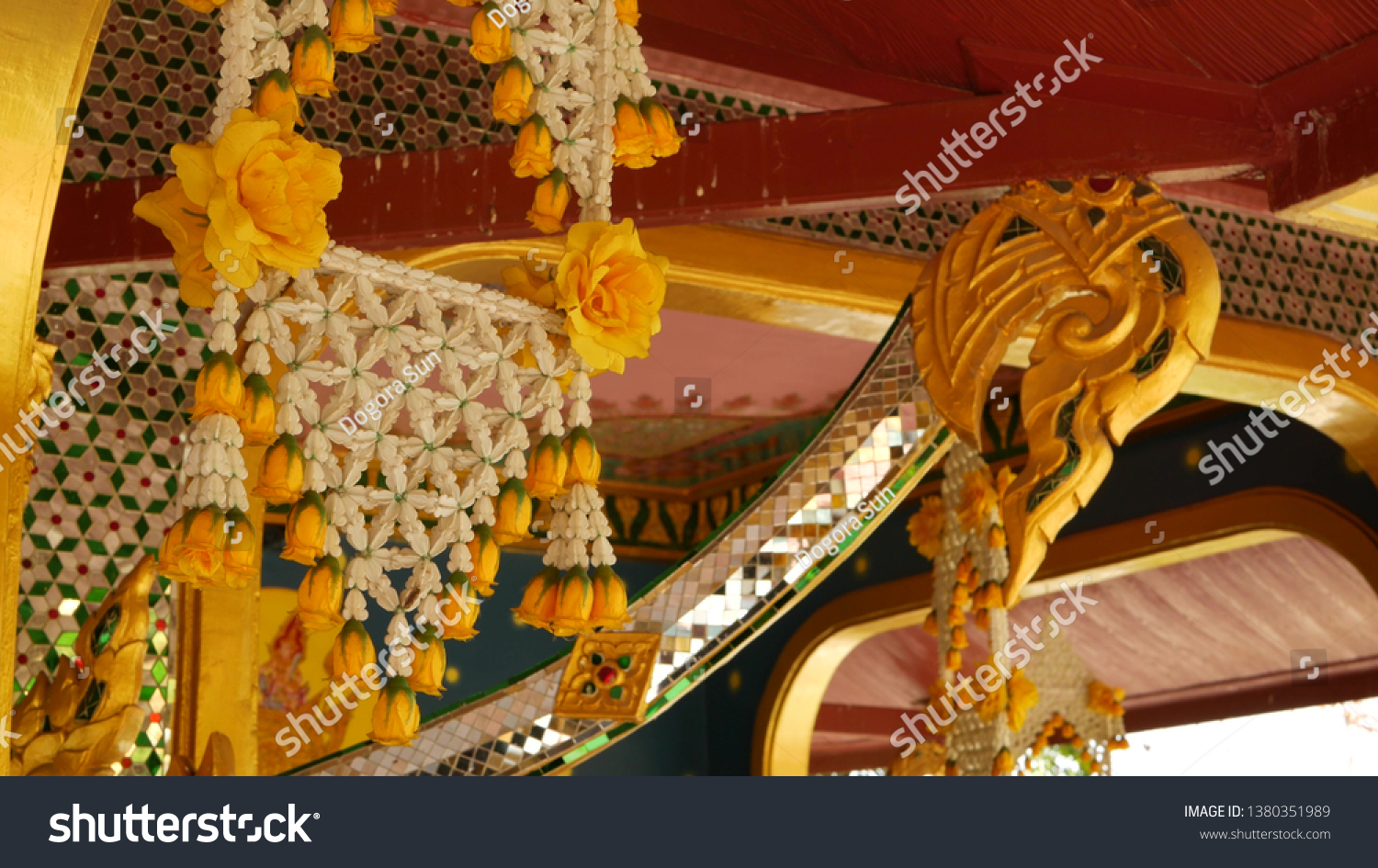 Floral interior decorations of oriental building. Beautiful flower compositions hanging on ceiling of ornamental building of buddist temple on sunny day in Thailand. #1380351989